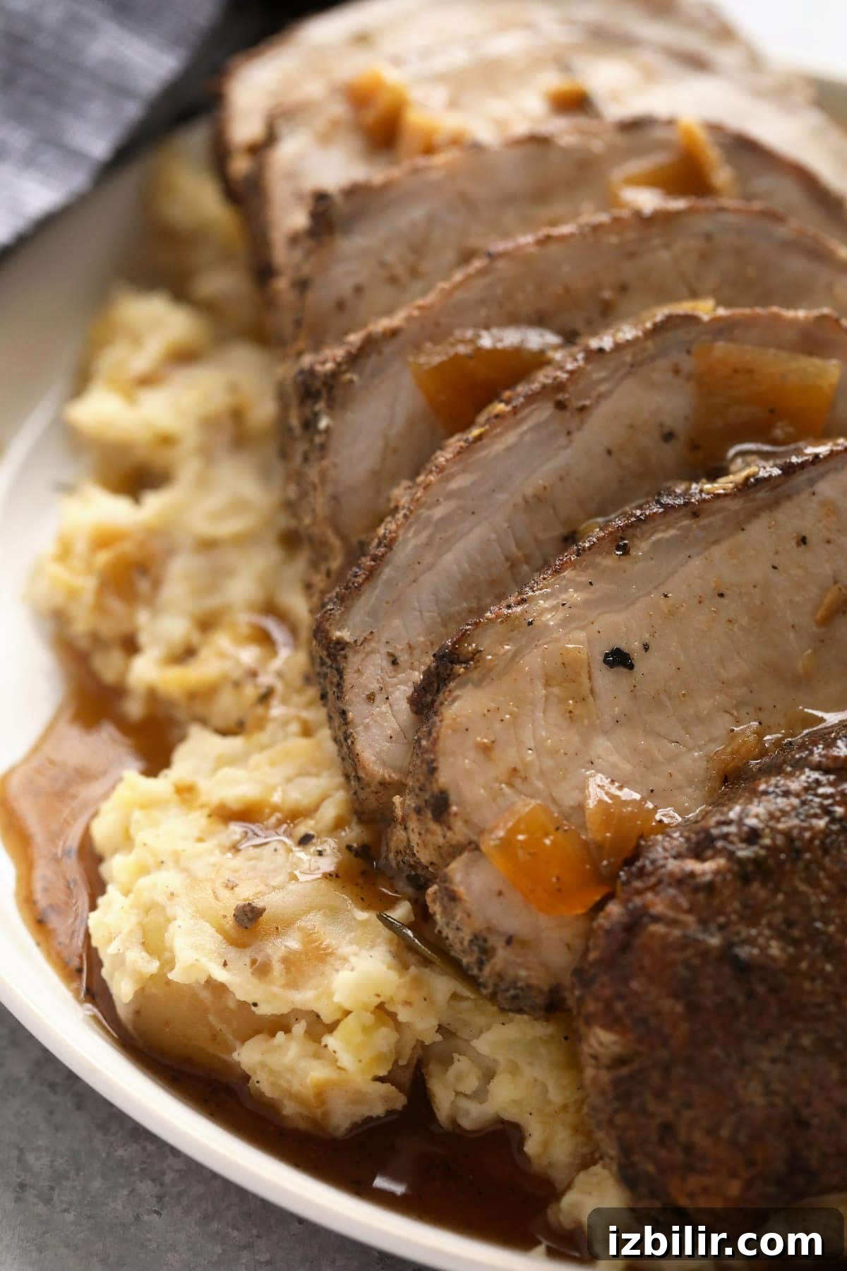 Slow cooker pork loin sliced and covered in gravy.