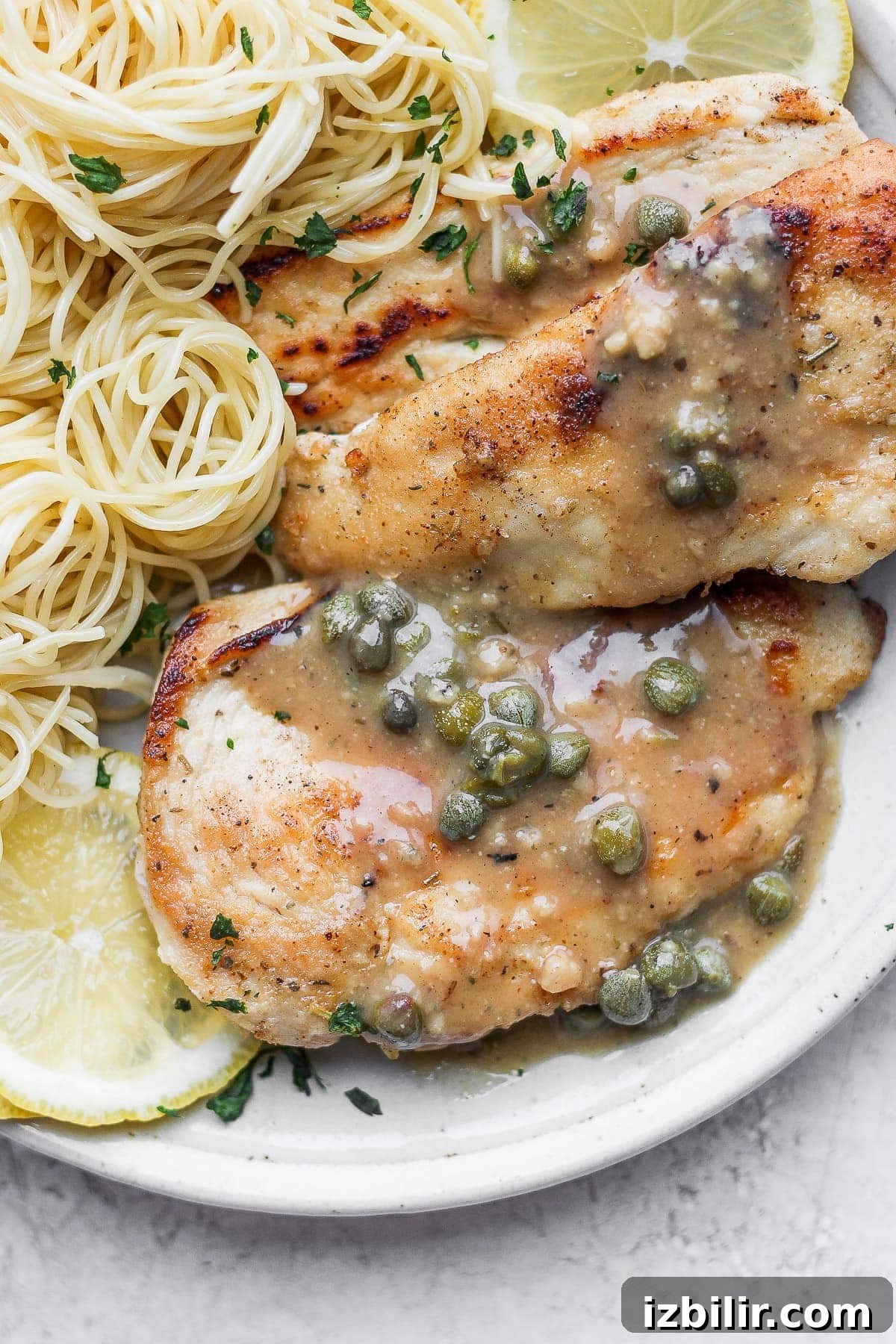 Chicken piccata on a plate with capers on top.