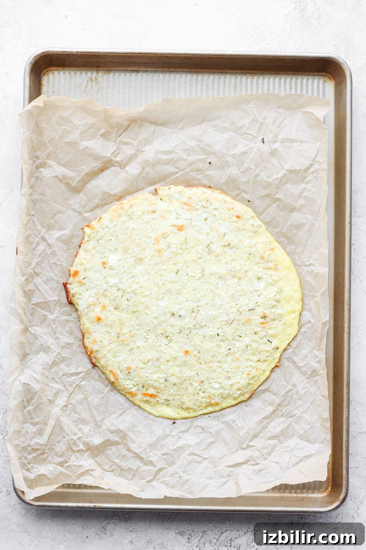 Gluten-Free Cauliflower Pizza Crust Recipe 8 Baked cauliflower pizza crust on parchment paper.