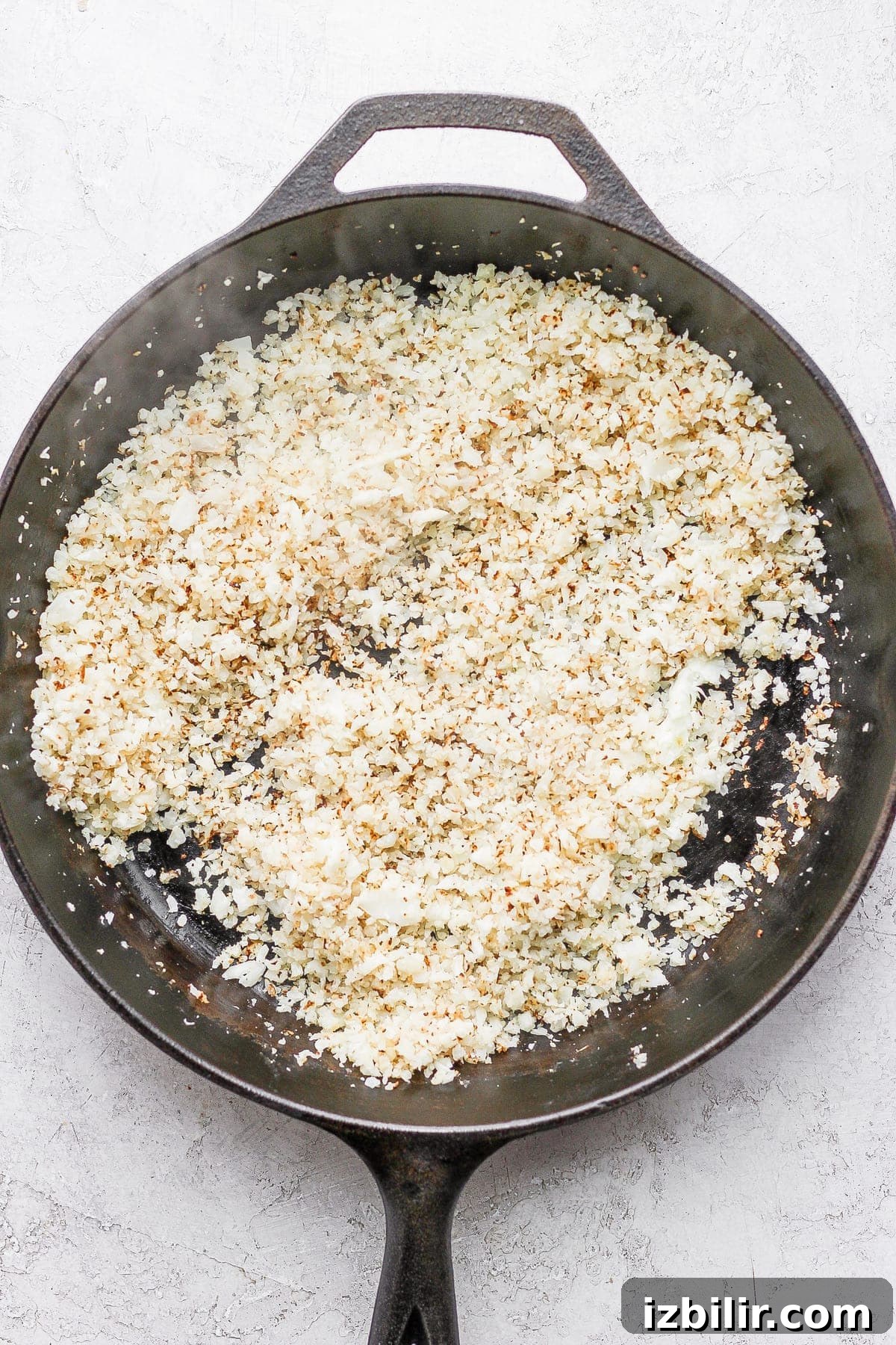 Riced cauliflower browning in a skillet riced cauliflower in a skillet being browned
