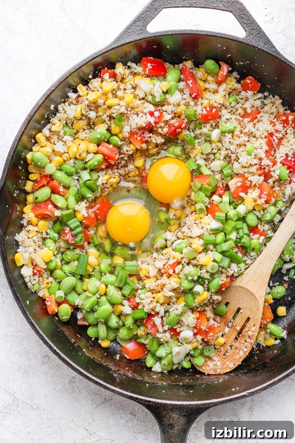 Eggs added to cauliflower fried rice cauliflower fried rice with 2 eggs cracked in the middle of the skillet