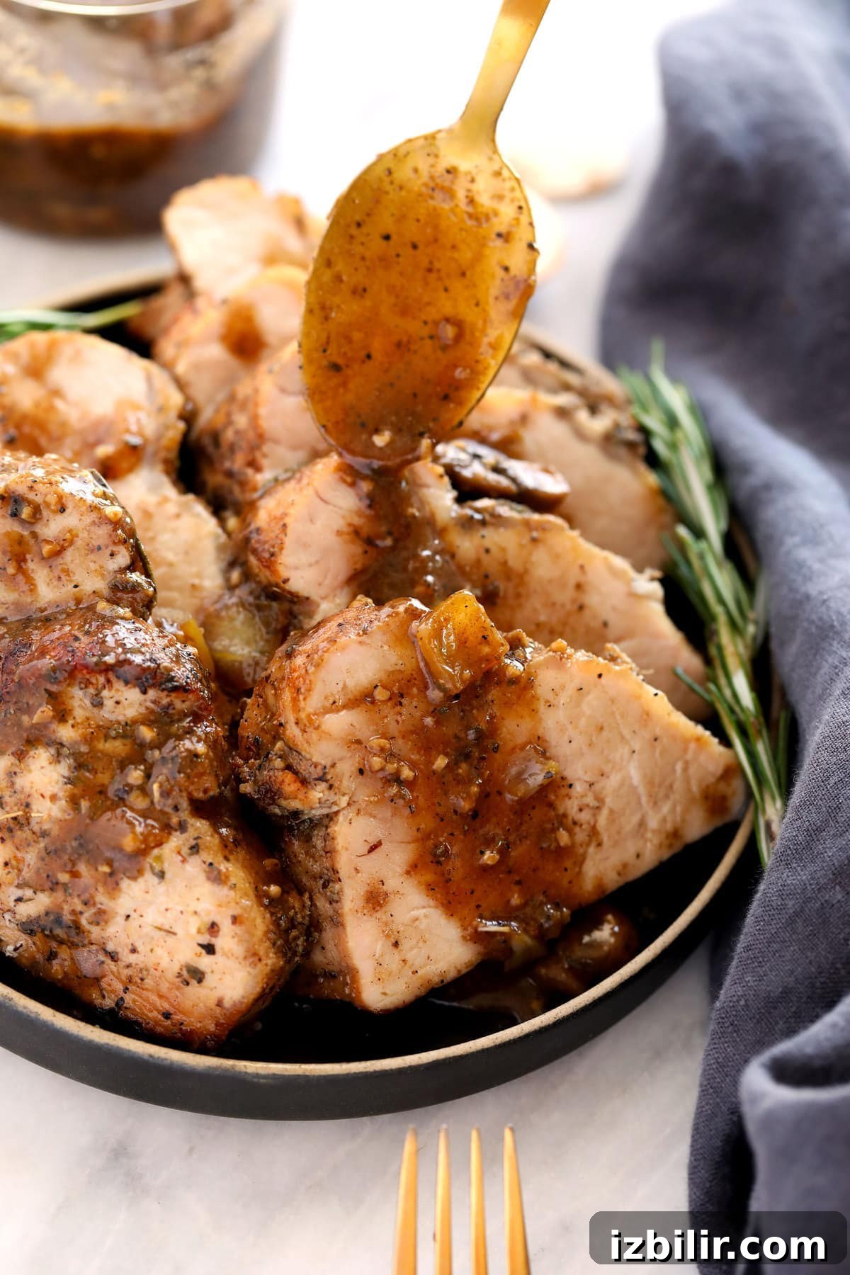 The most delicious baked pork tenderloin recipe made with an incredible mushroom gravy all in one dish! pouring sauce on pork tenderloin.