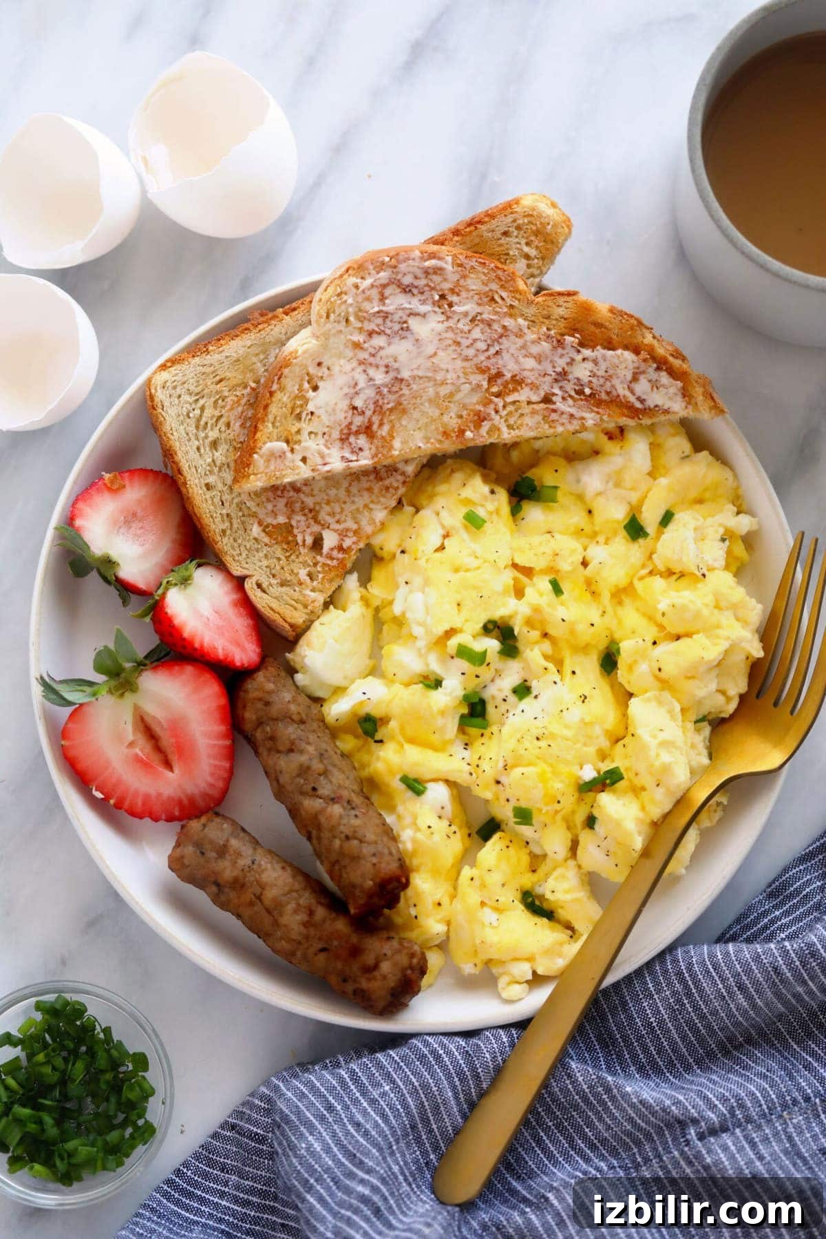 Make fluffy scrambled eggs every time with this perfect scrambled eggs recipe. scrambled eggs on a plate with fresh fruit and toast