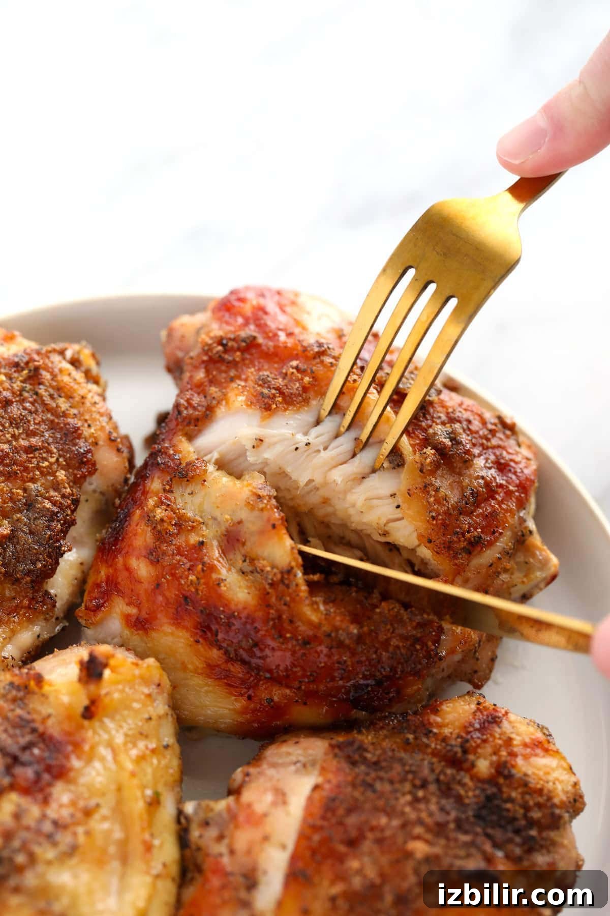 Crispy Oven-Baked Chicken Thighs with Garlic and Herbs 2 Cutting through a chicken thigh on a plate.