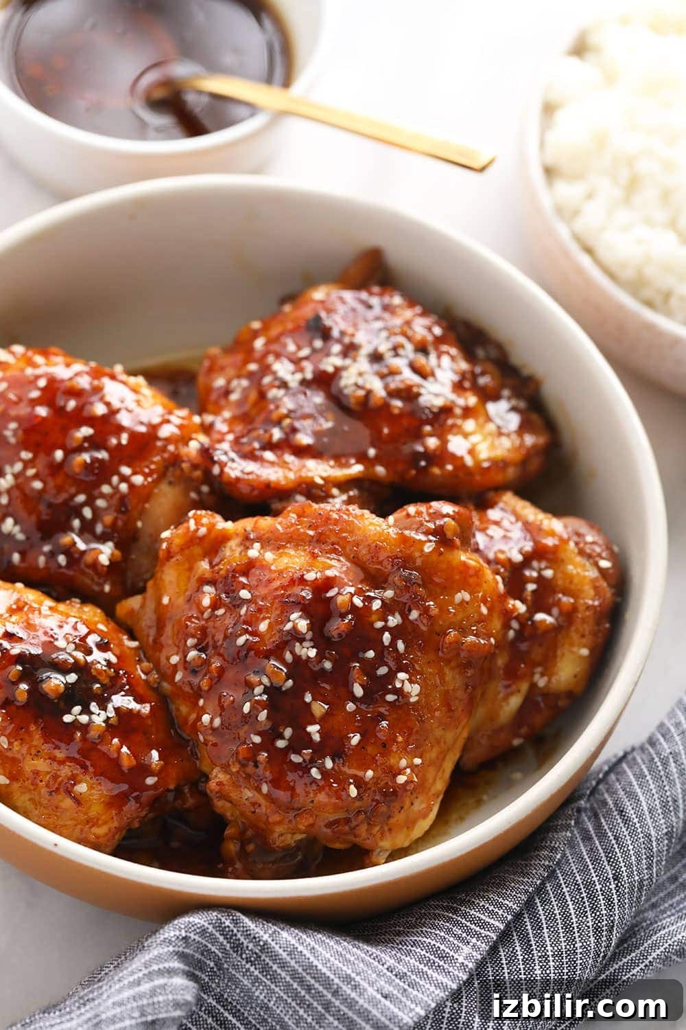 Crispy Oven-Baked Chicken Thighs with Garlic and Herbs 9 Chicken thighs in a bowl with sesame seeds on top.