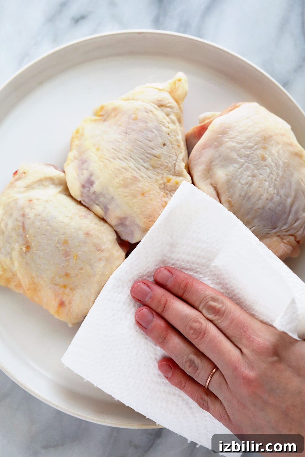 Crispy Oven-Baked Chicken Thighs with Garlic and Herbs 3 Removing moisture from the chicken thighs with a paper towel.