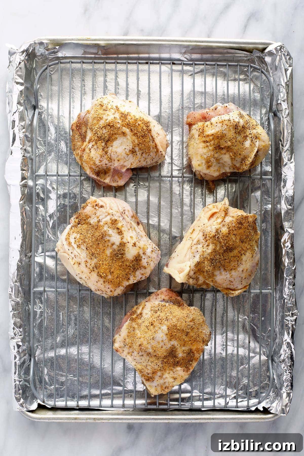 Crispy Oven-Baked Chicken Thighs with Garlic and Herbs 6 Chicken thighs on a baking sheet with seasonings.