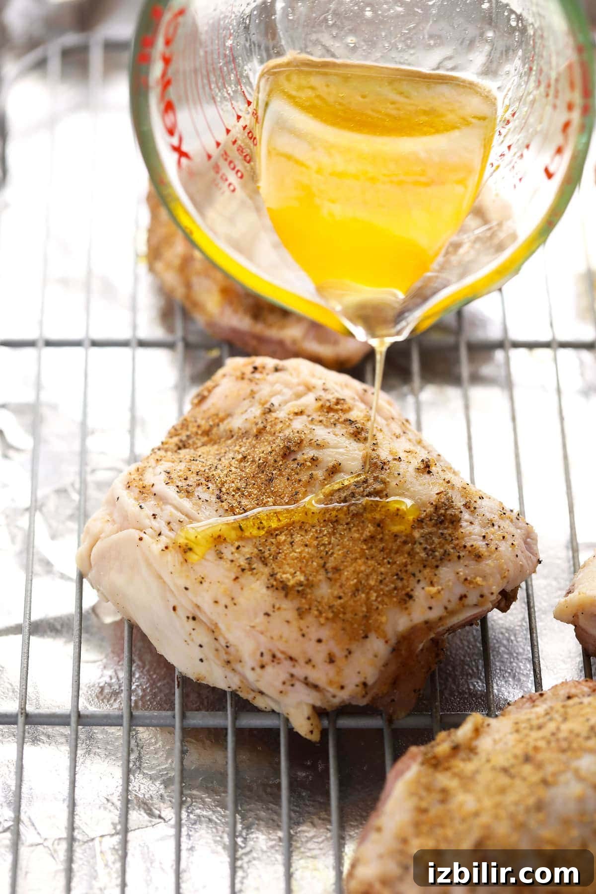 Crispy Oven-Baked Chicken Thighs with Garlic and Herbs 7 Pouring oil on top of chicken thighs.