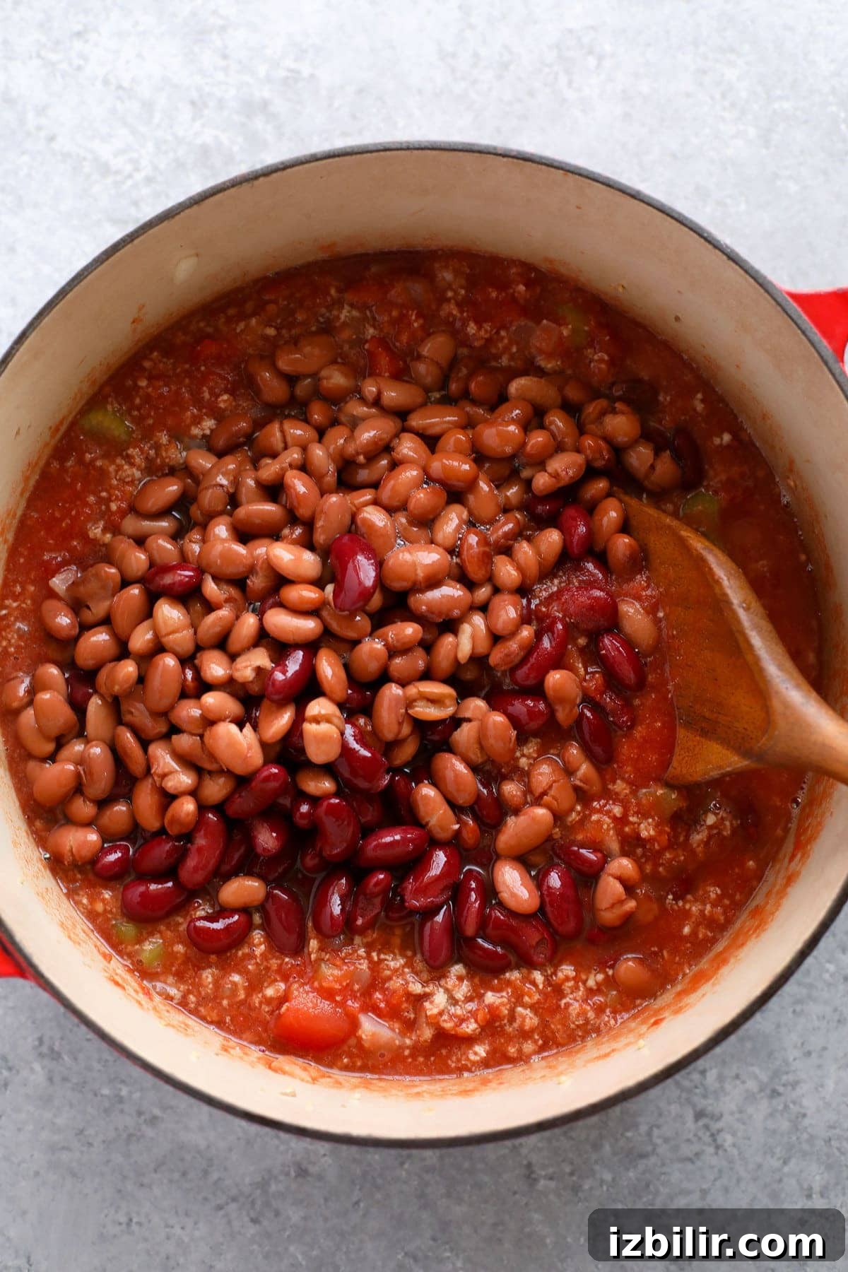 Beans being added to a dutch oven to make turkey chili.
