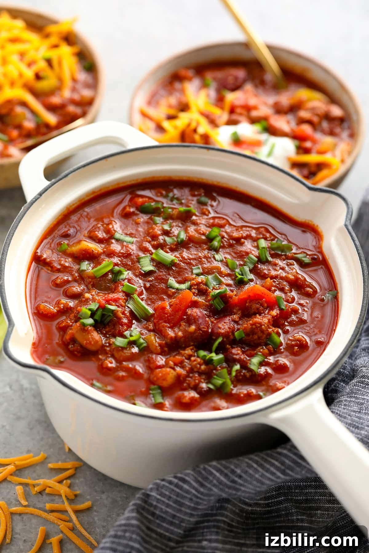Turkey chili topped with green onions in a pot.