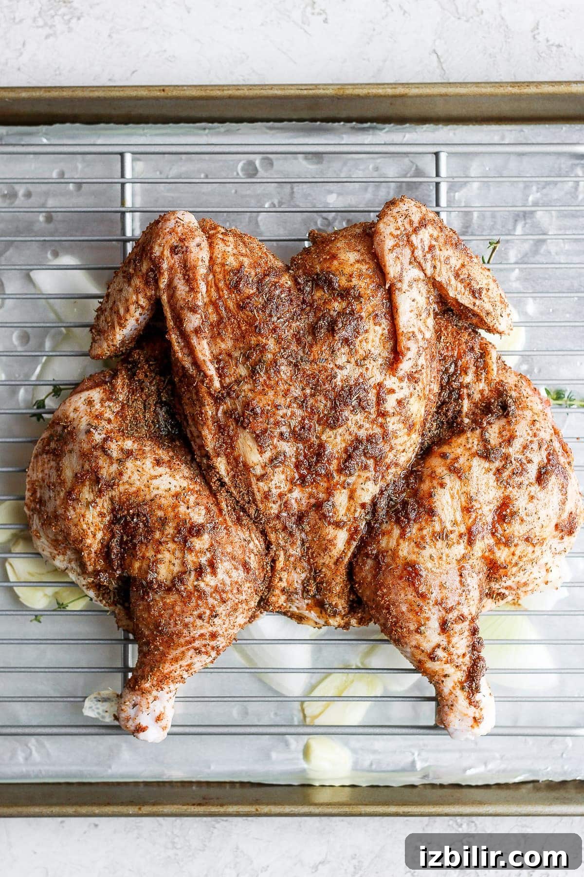 A raw spatchcock chicken on a making sheet.