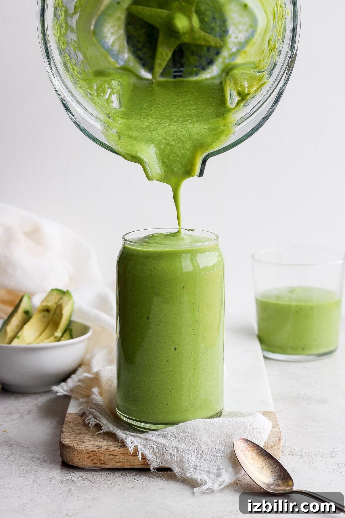 avocado smoothie being poured from a blender to a glass