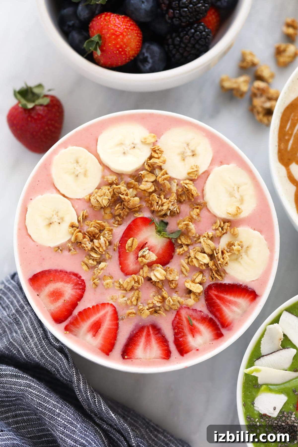 strawberry smoothie with banana slices, granola, and strawberries