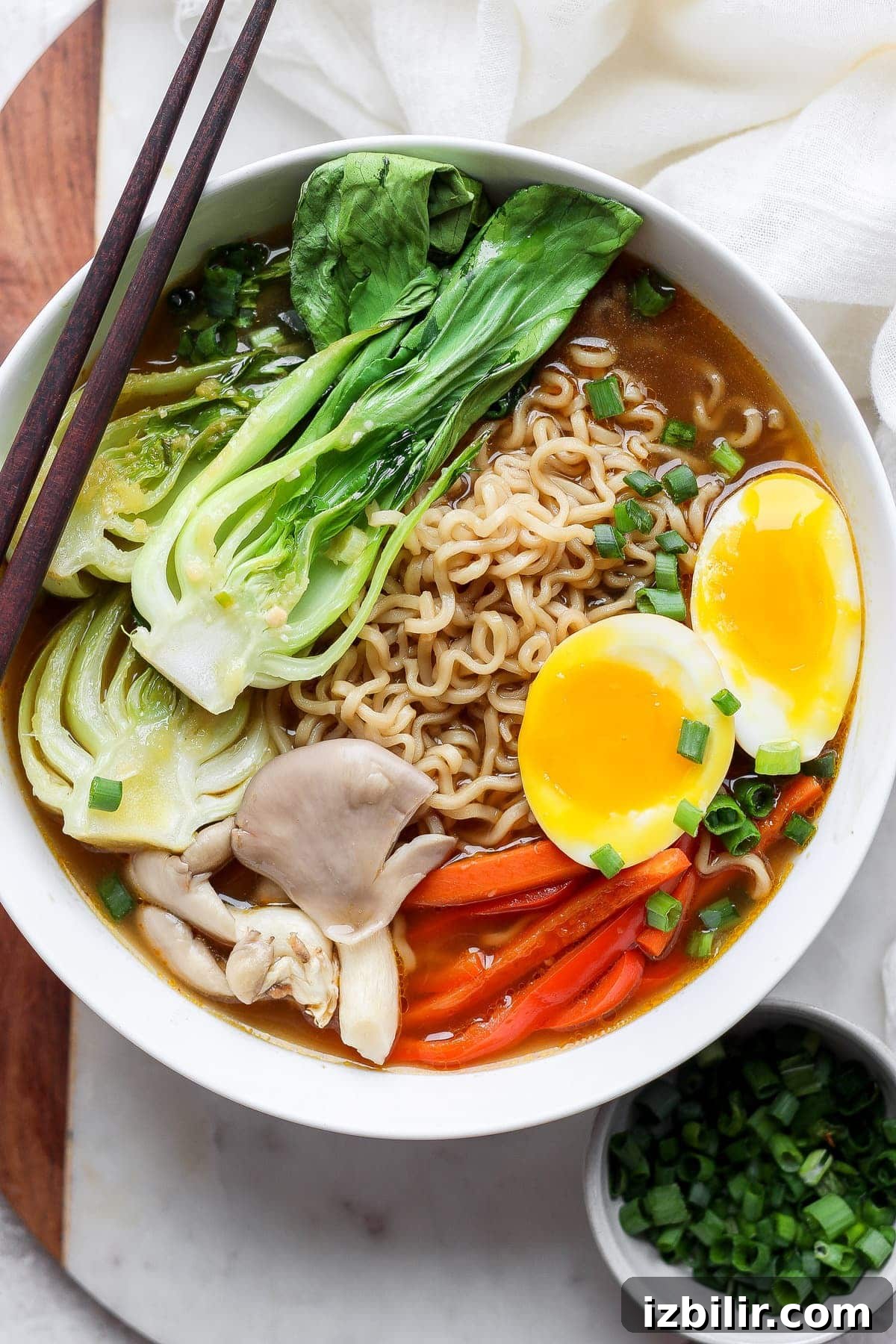 Ramen in a bowl with soft boiled eggs and vegetables.