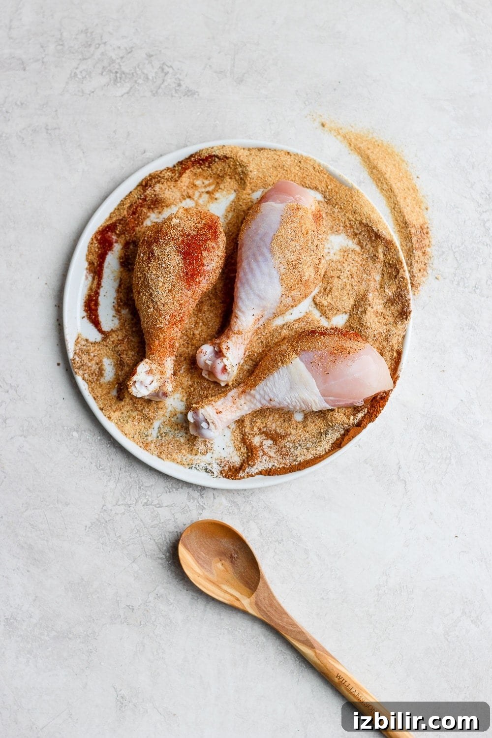 Chicken legs ready for the grill chicken legs rolled in dry rub on a plate ready to be grilled