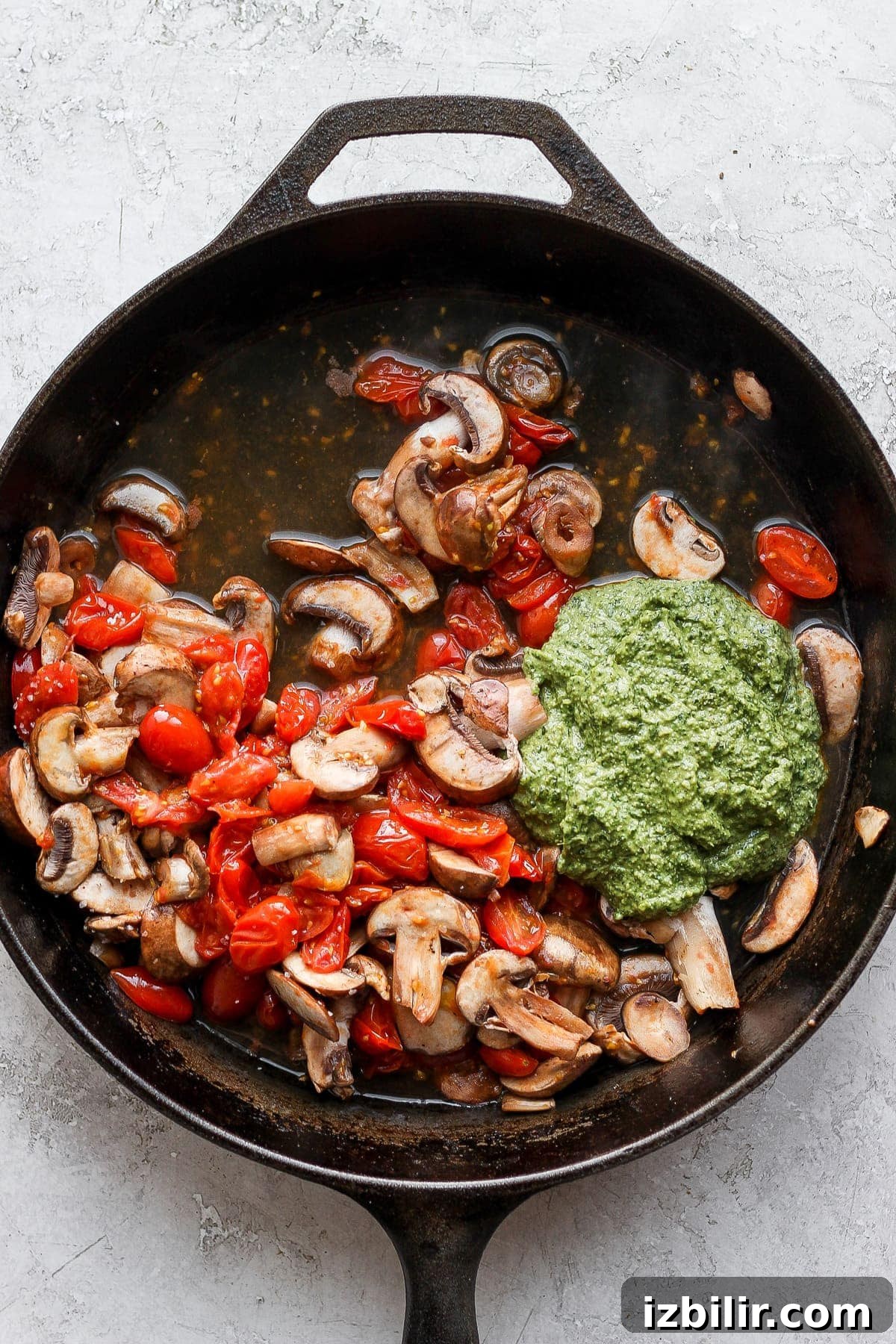 Pesto and vegetables in a cast iron skillet.