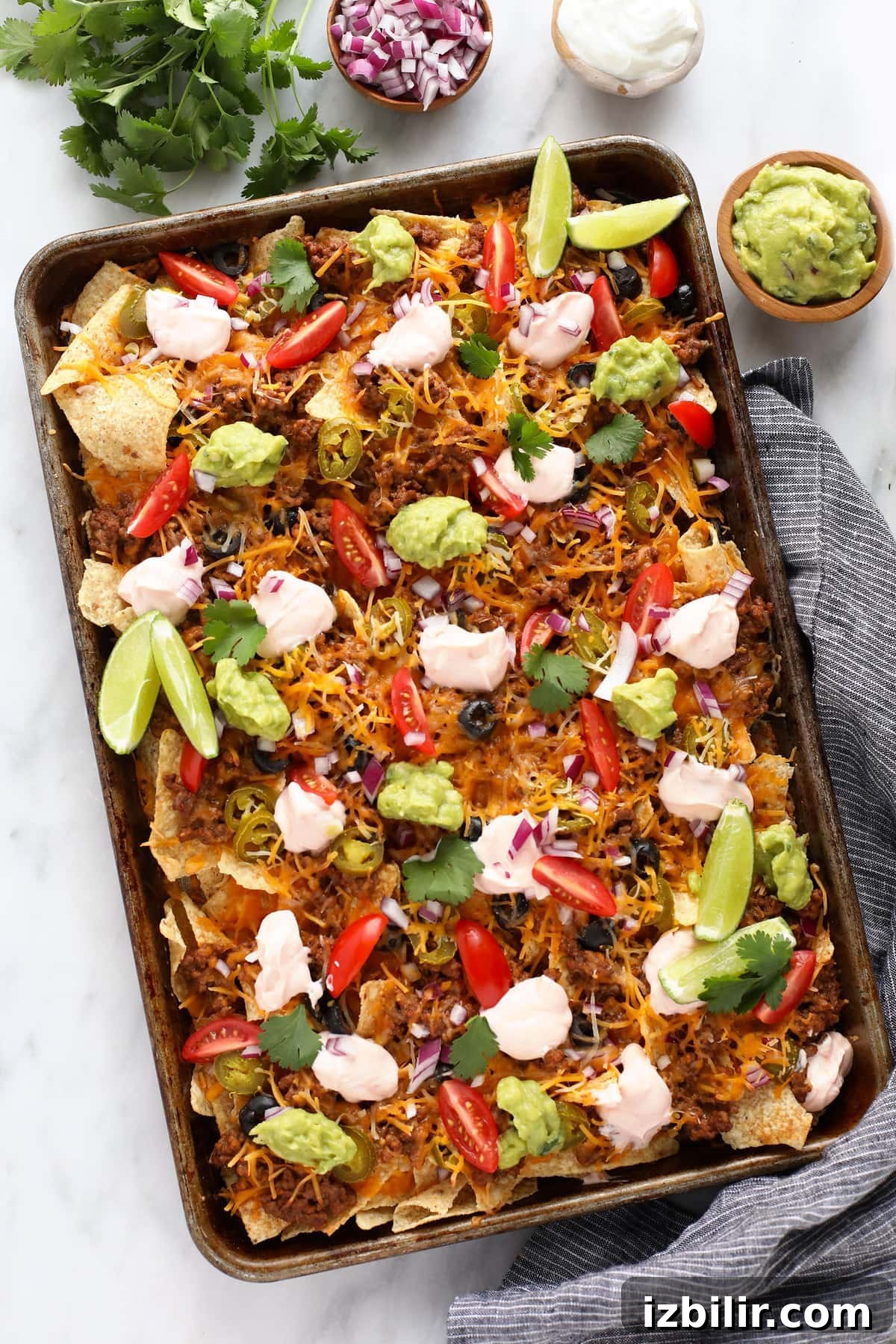 beef nachos on baking sheet with guacamole