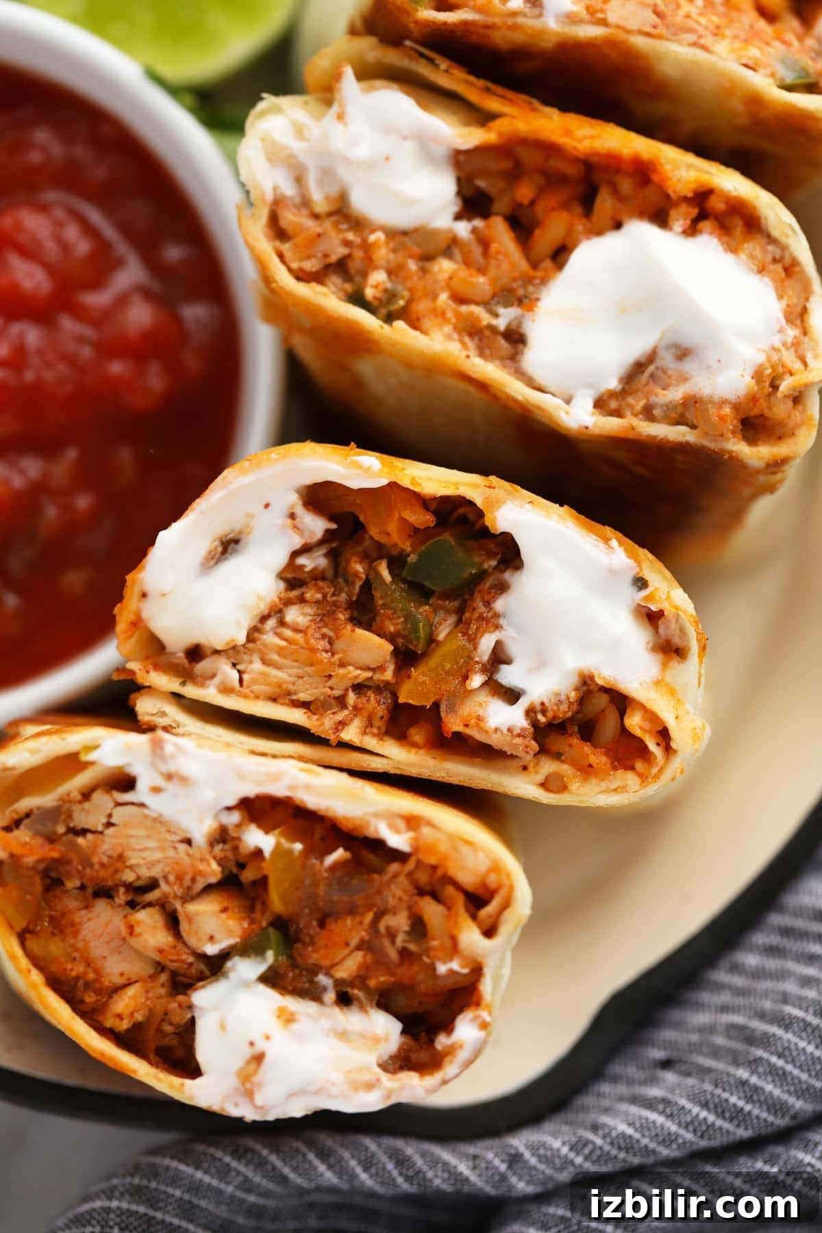 Shredded chicken burritos cut in half and topped with sour cream.