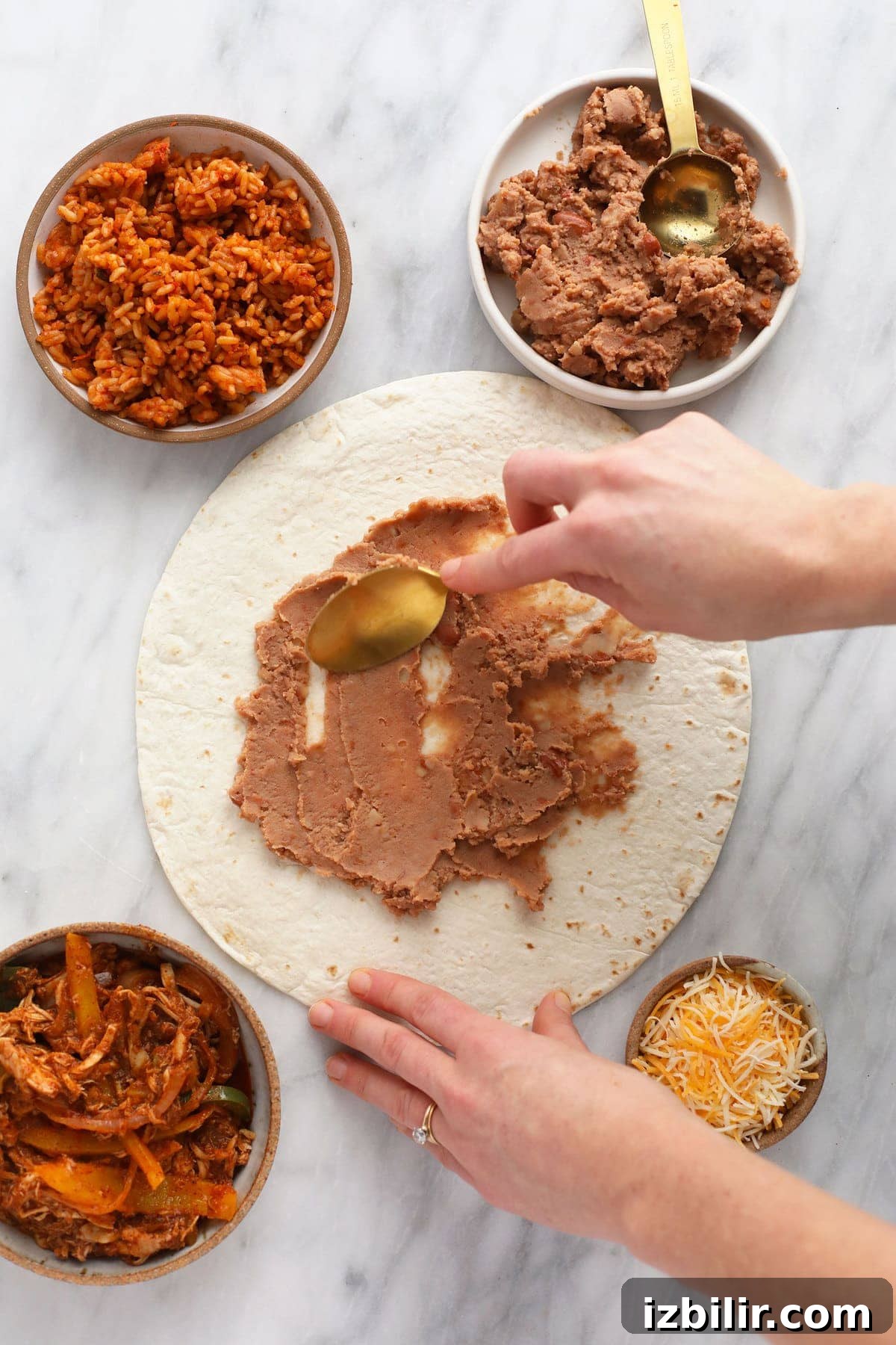 Refried beans being spread on a tortilla.