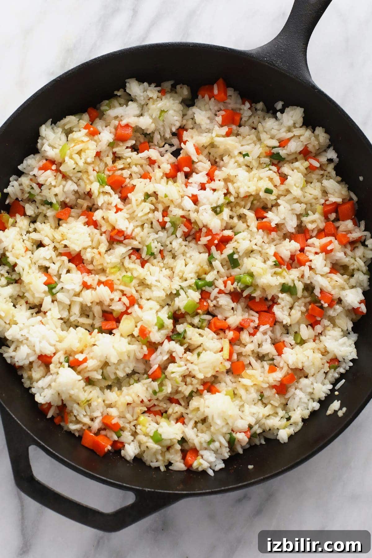 frying rice and veggies in cast iron pan