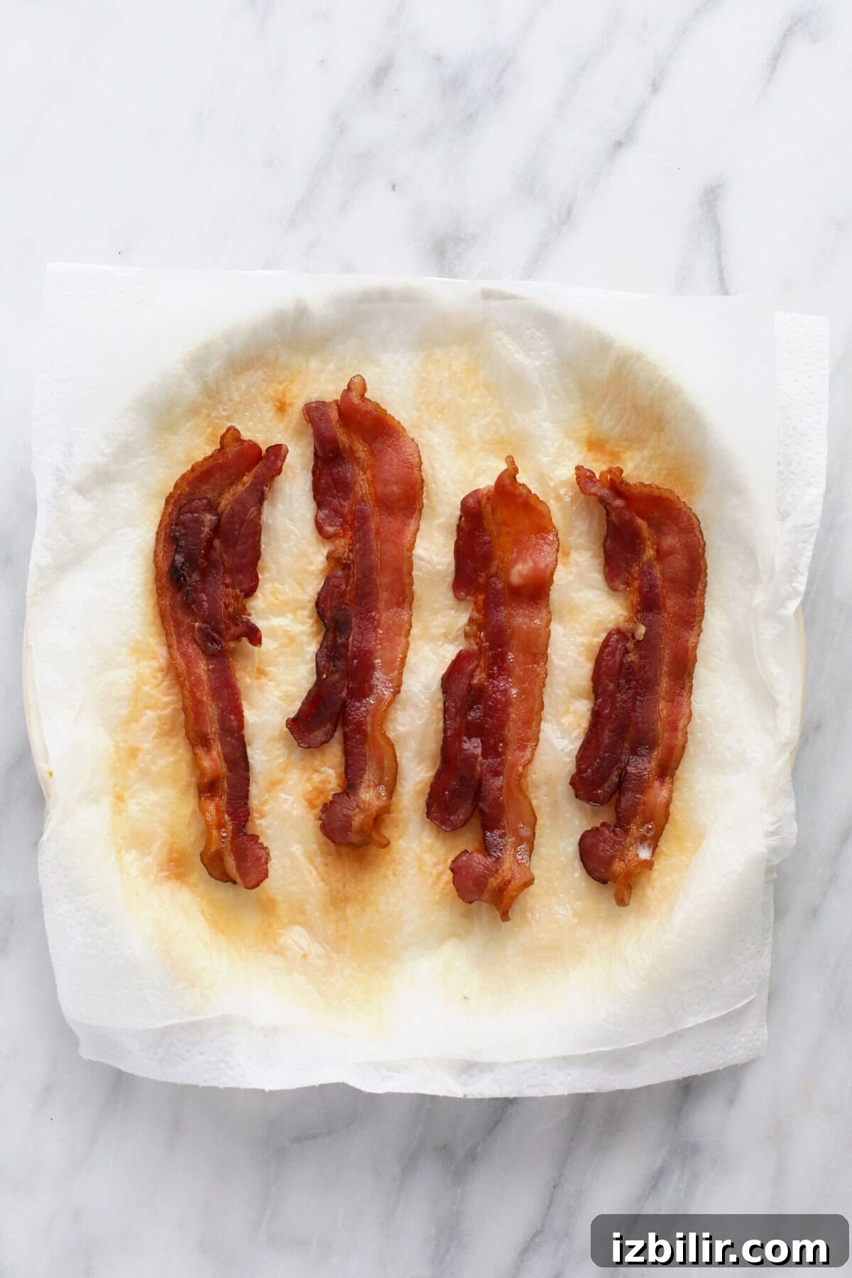 Crispy Microwave Bacon in Minutes 4 Cooked bacon on a plate that is covered in paper towel.