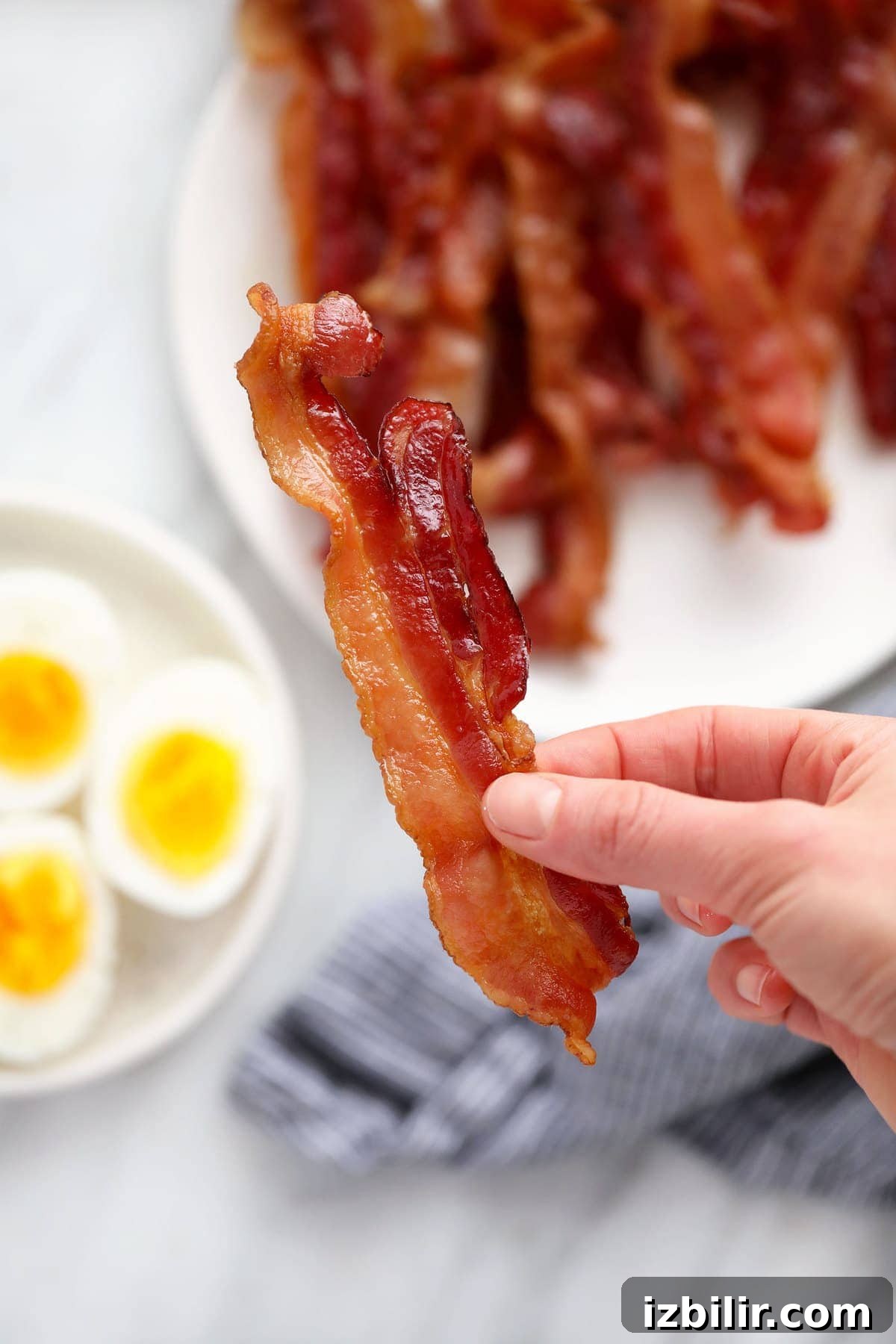 Crispy Microwave Bacon in Minutes 5 A hand holding a piece of bacon.