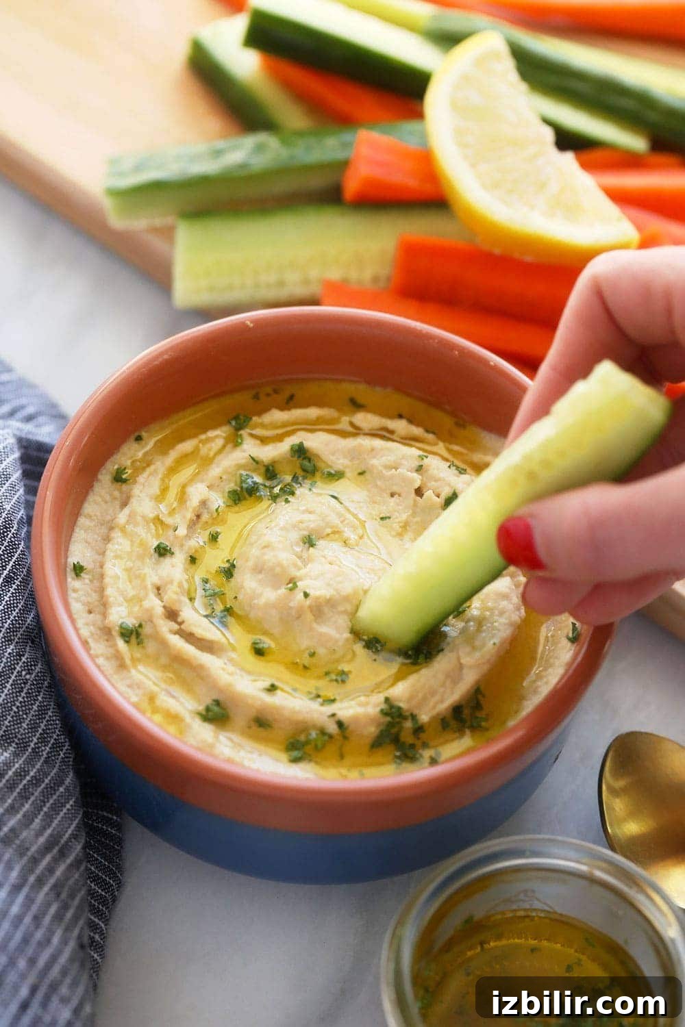 Hummus with veggie lemon garlic hummus in a bowl with a veggie dipped in it