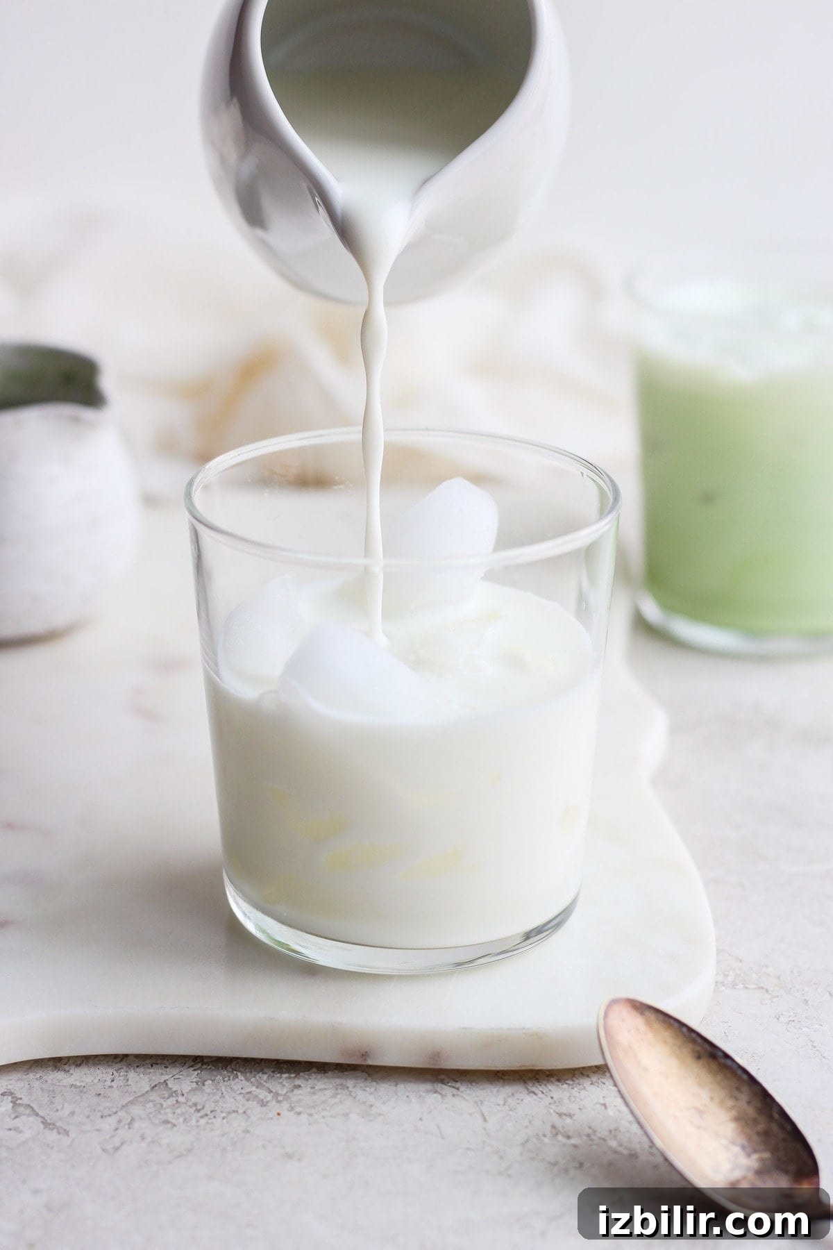How to Make an Iced Matcha Latte at Home 4 Pouring almond milk and maple syrup mixture over ice.