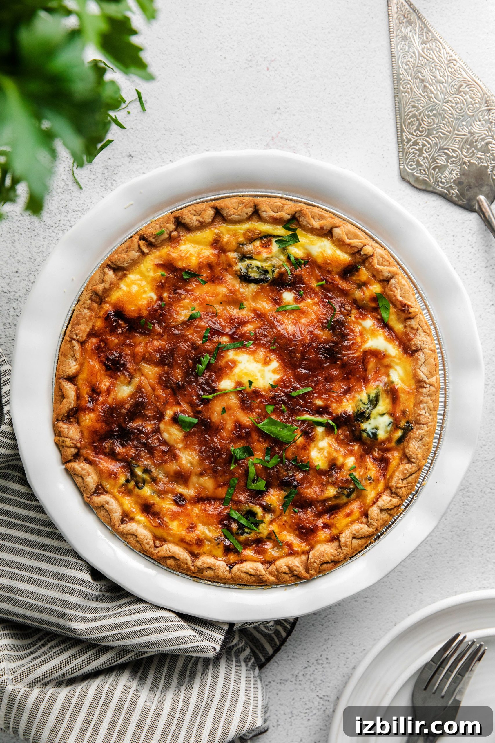 Spinach Quiche Recipe with Flaky Pastry Crust 7 A baked spinach quiche with parsley sprinkled on top.