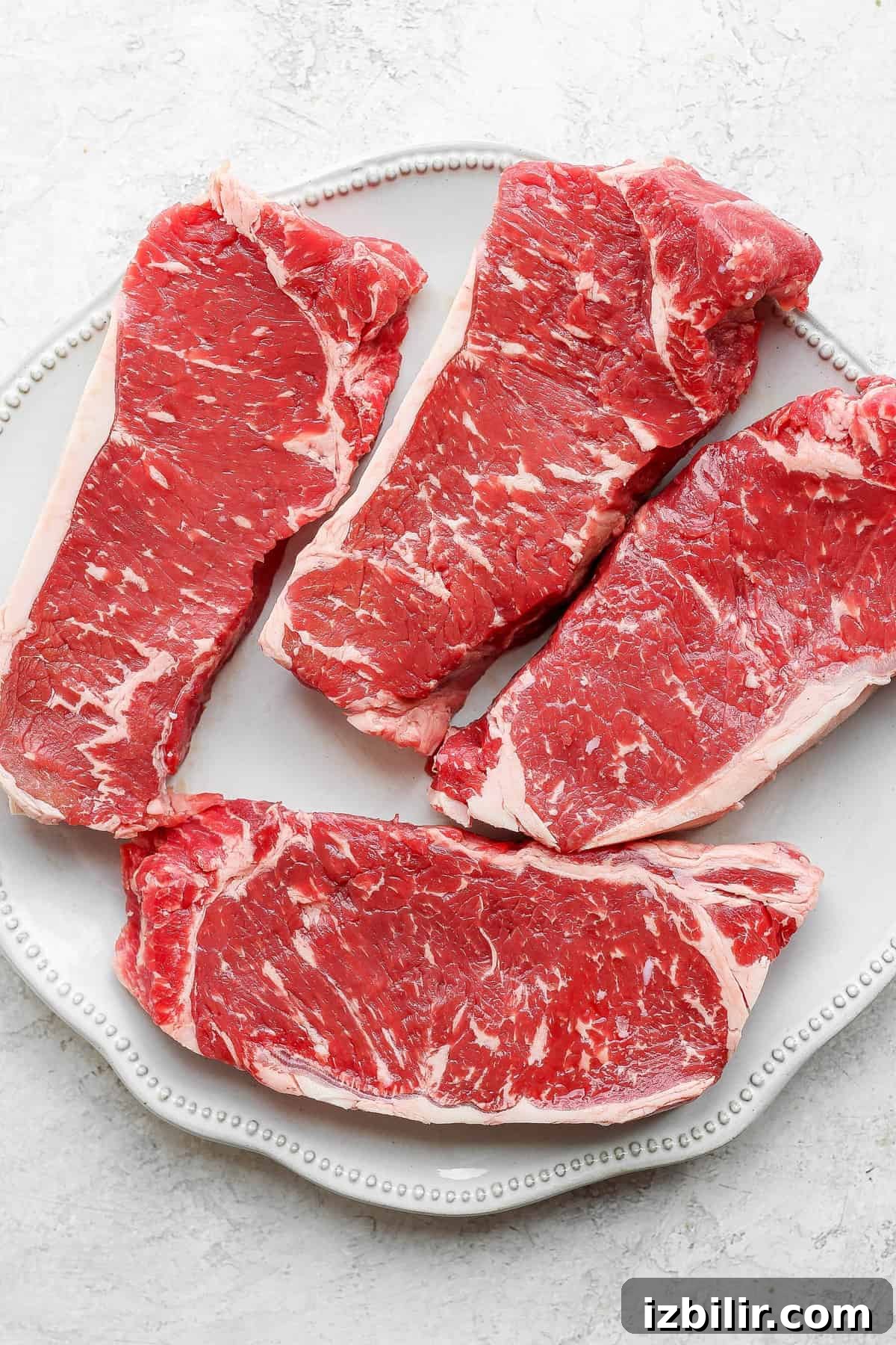 New York strip steaks 4 large New York steaks on a plate.