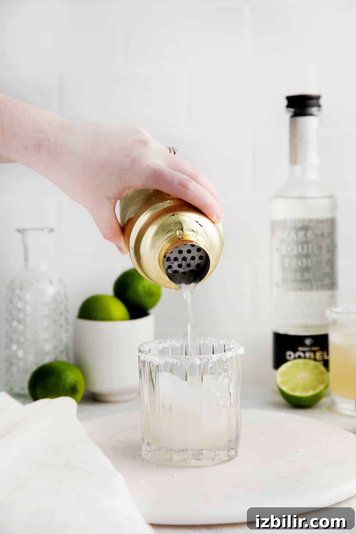 Classic Margarita Recipe: Tangy Lime and Tequila Cocktail 6 Pouring the margarita into a cocktail glass.