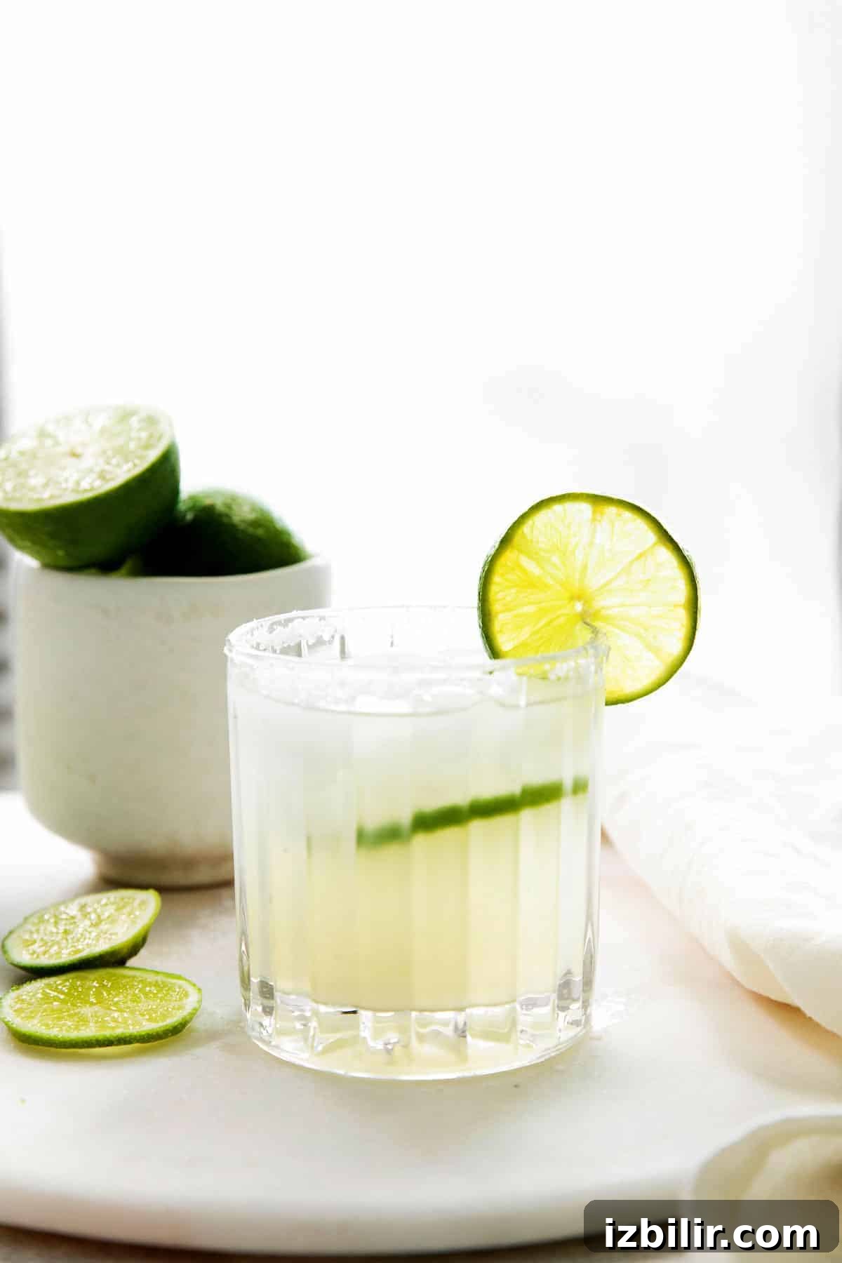 Classic Margarita Recipe: Tangy Lime and Tequila Cocktail 8 A cocktail glass full of margarita with a fresh lime slice.