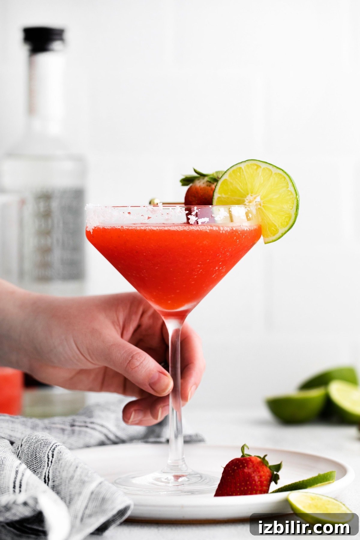 hand holding strawberry margarita in glass
