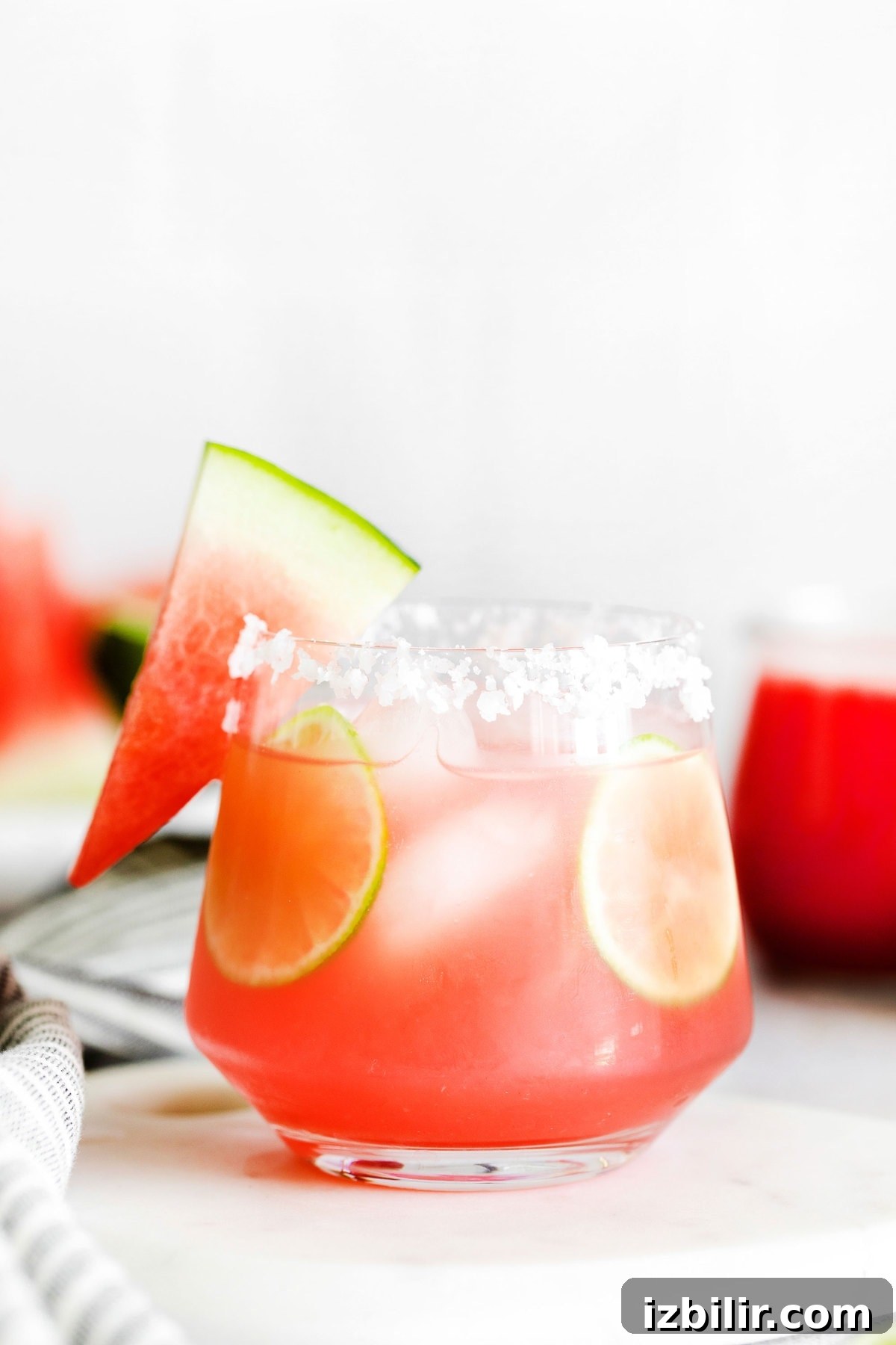 Watermelon margarita served in a glass with a slice of watermelon on the rim.