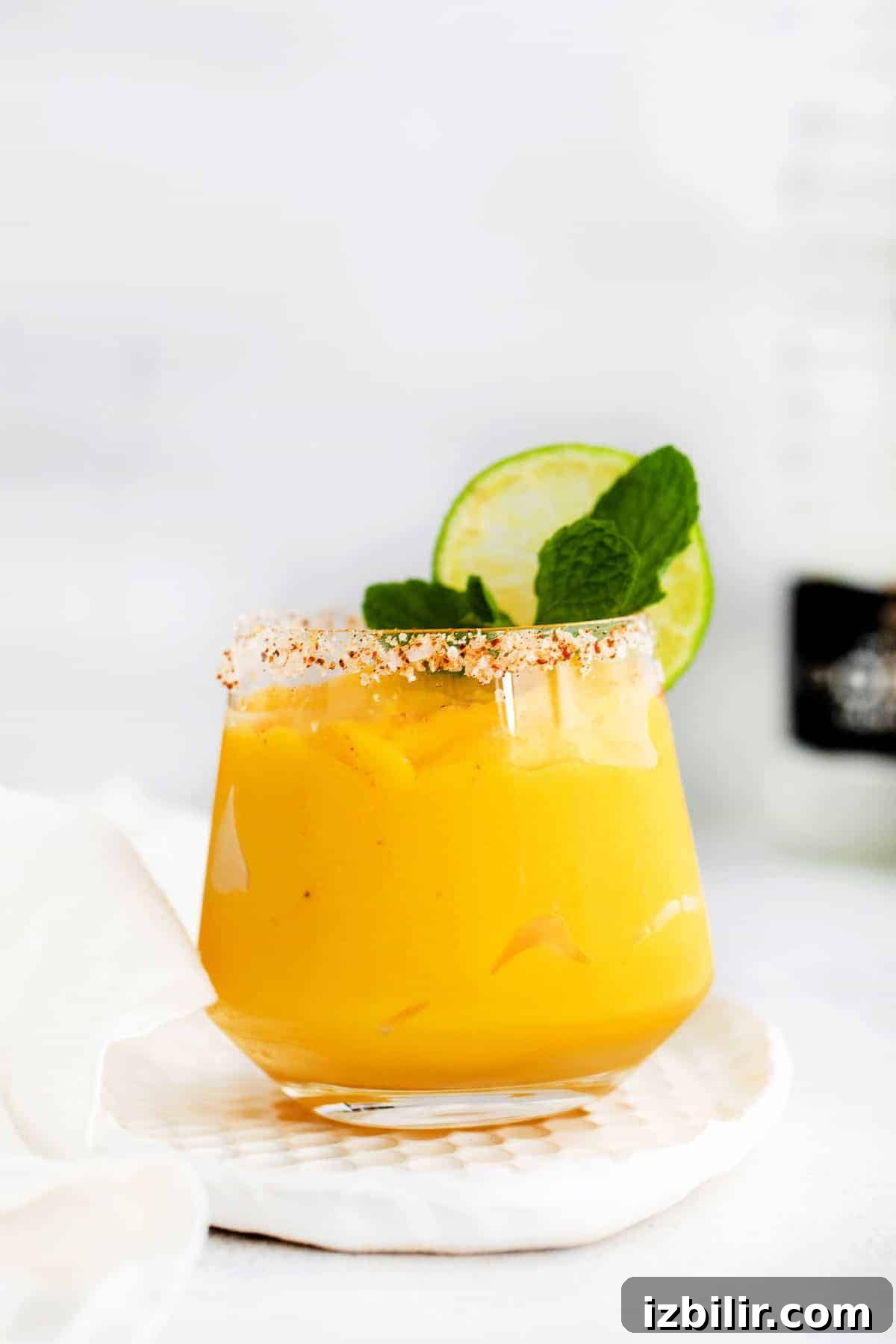Frozen Mango Margarita Recipe with Tequila 2 mango margarita in glass with lime.