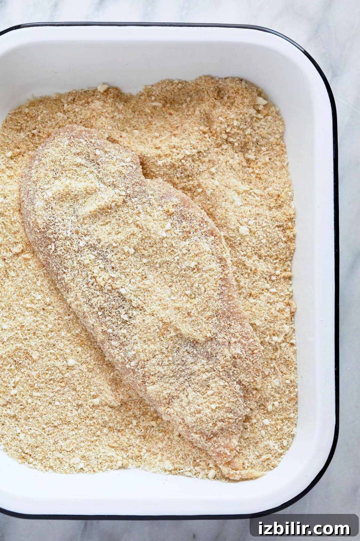 dredging chicken in bread crumbs and parmesan cheese