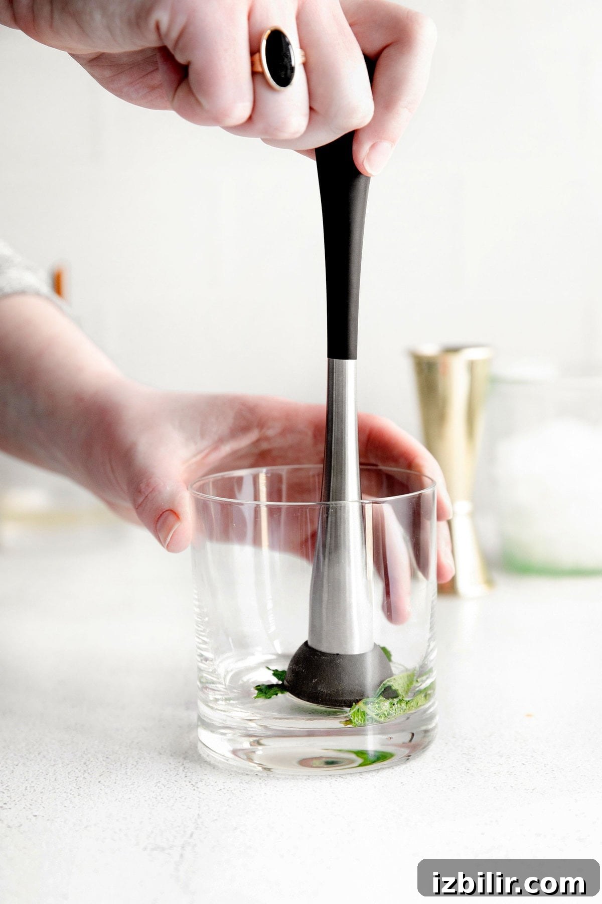 Classic Bourbon Mint Julep Cocktail Recipe 4 mint being muddled in the bottom of a glass for mint juleps.