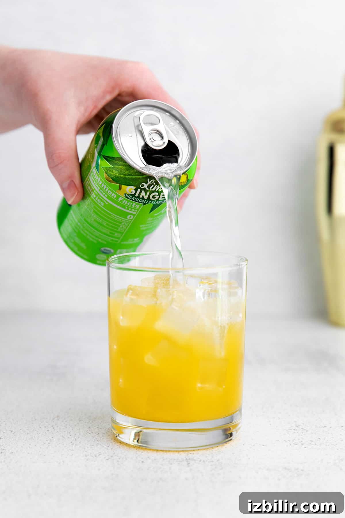 pouring sparkling water into a virgin margarita.