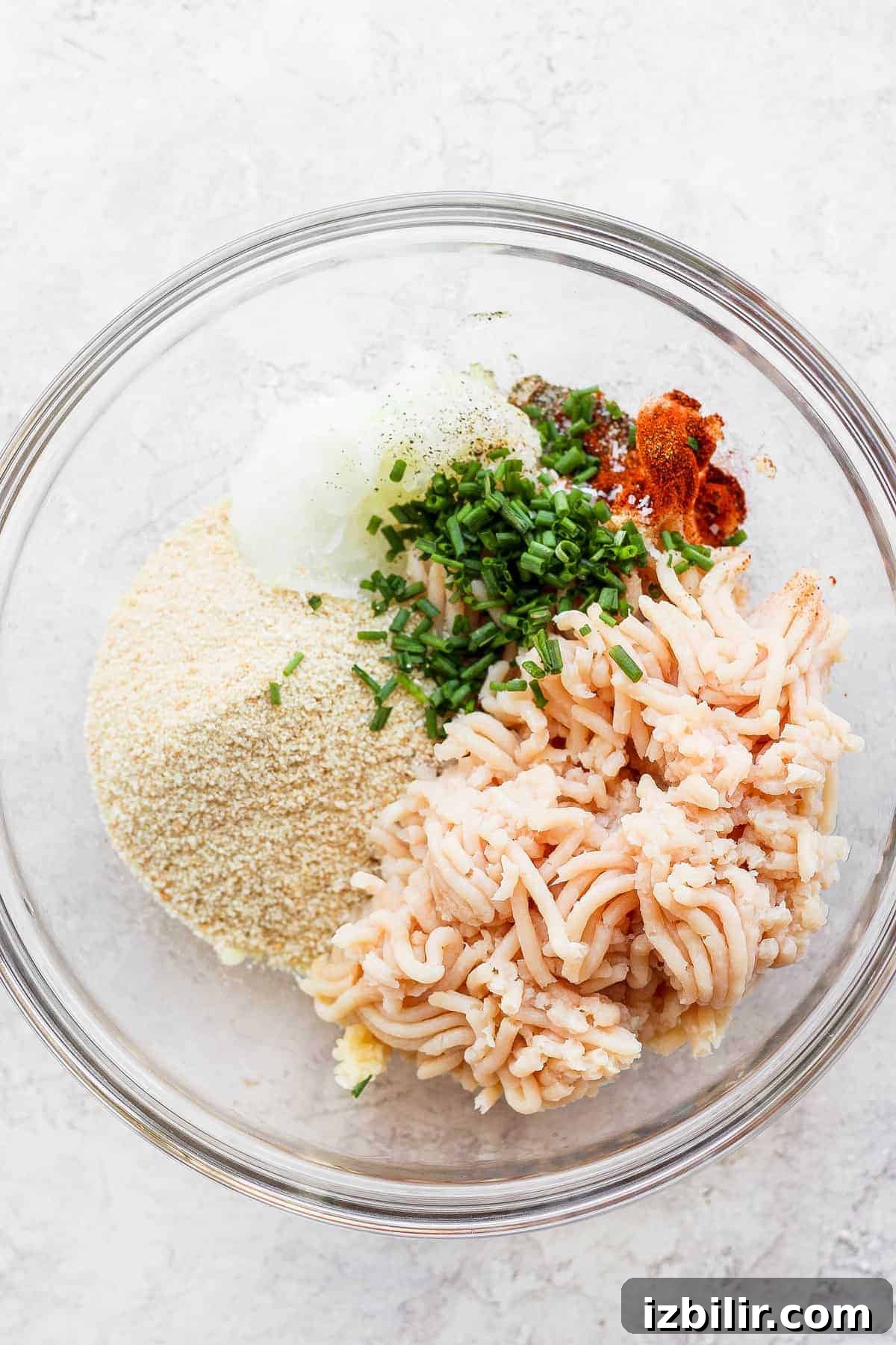ground chicken, breadcrumbs, onion, and chives in bowl.