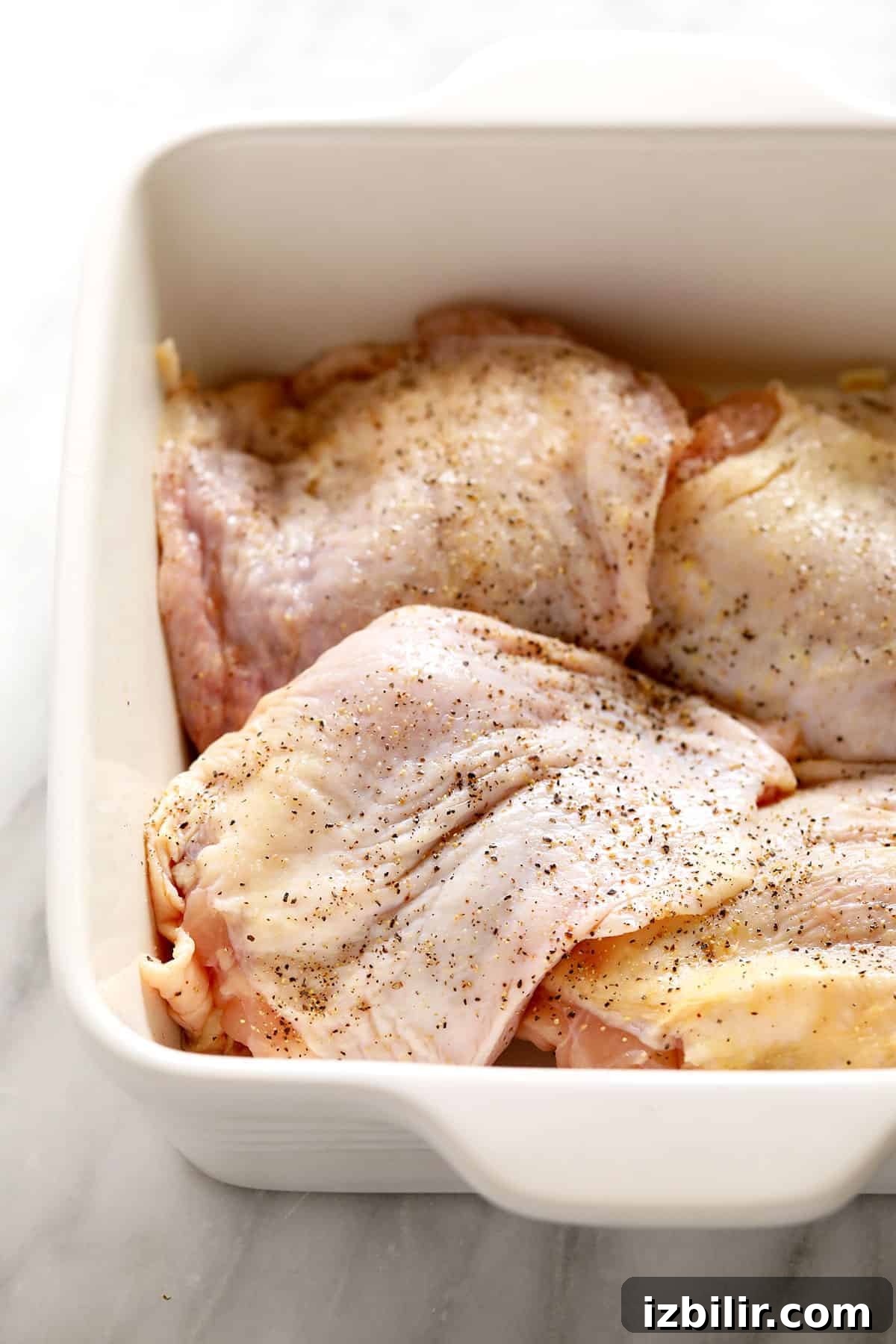 How to Smoke Chicken Thighs for Juicy, Crispy Skin 3 Chicken thighs marinating in a casserole dish.