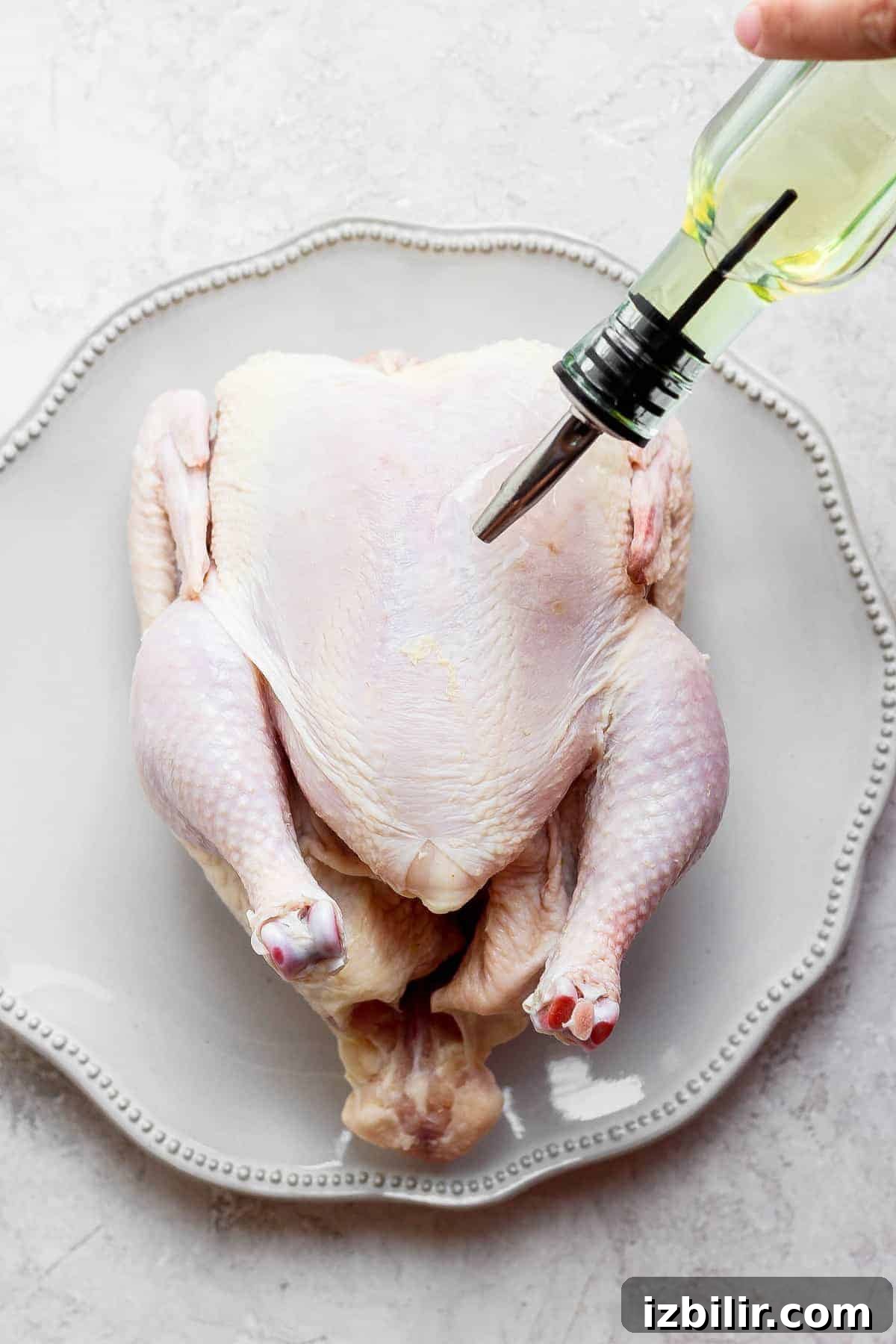 Drizzling olive oil over a whole chicken.