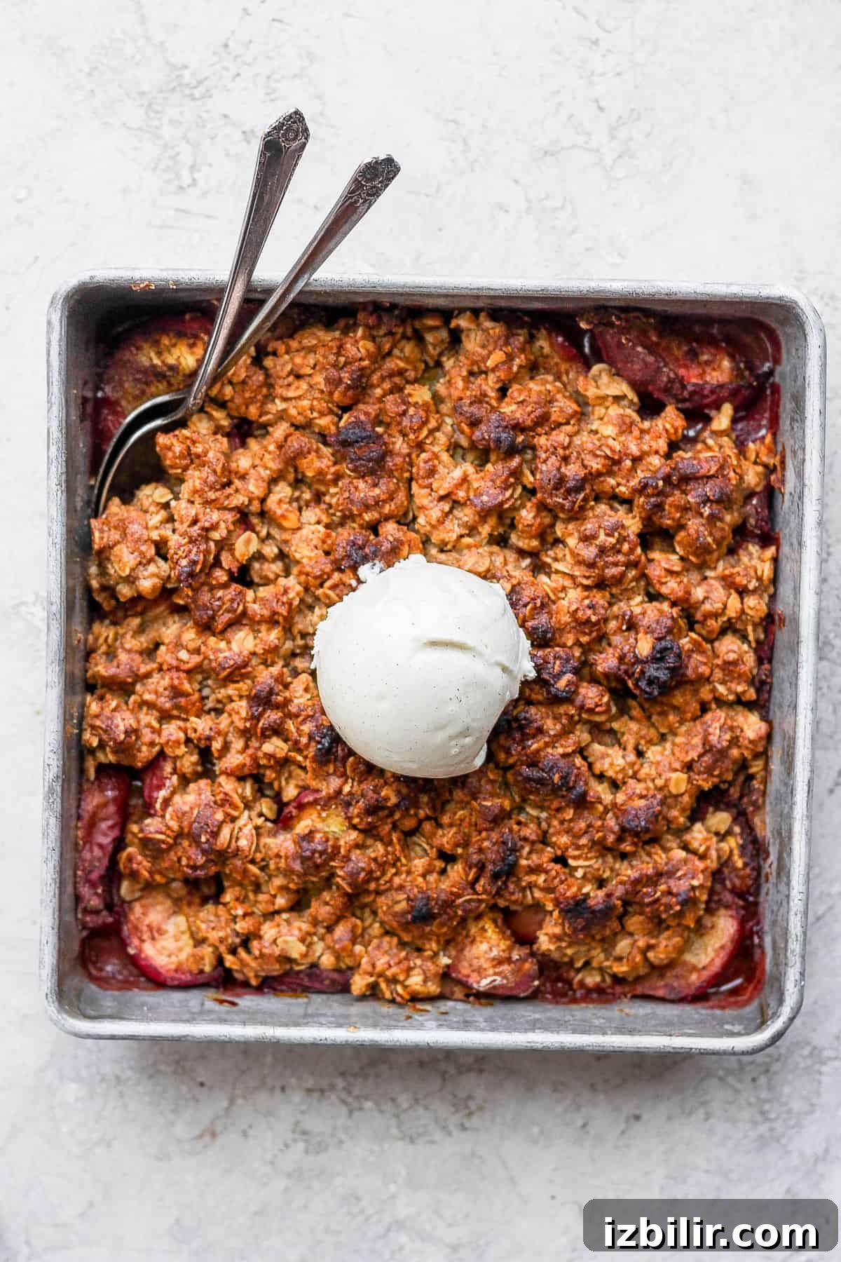 Nothing screams summer like a perfect peach crisp! Whip up this easy dessert that comes complete with a golden crumble topping. Enjoy! Peach crisp topped with a scoop of vanilla ice cream in a square baking dish.
