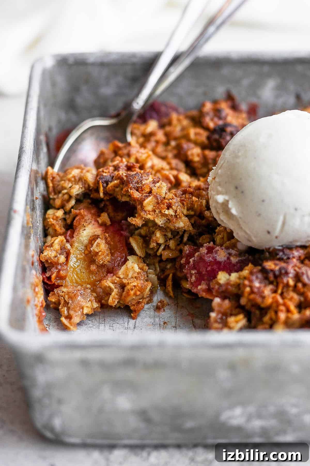 Serve warm with vanilla ice cream. close up of a peach crisp with a scoop of vanilla ice cream