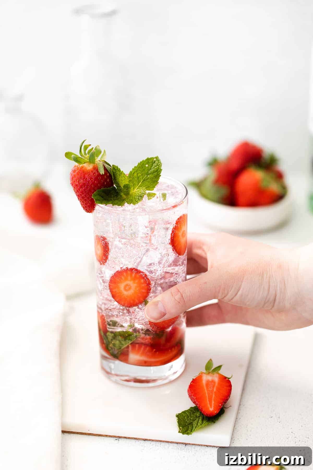 Hand holding a strawberry mojito glass