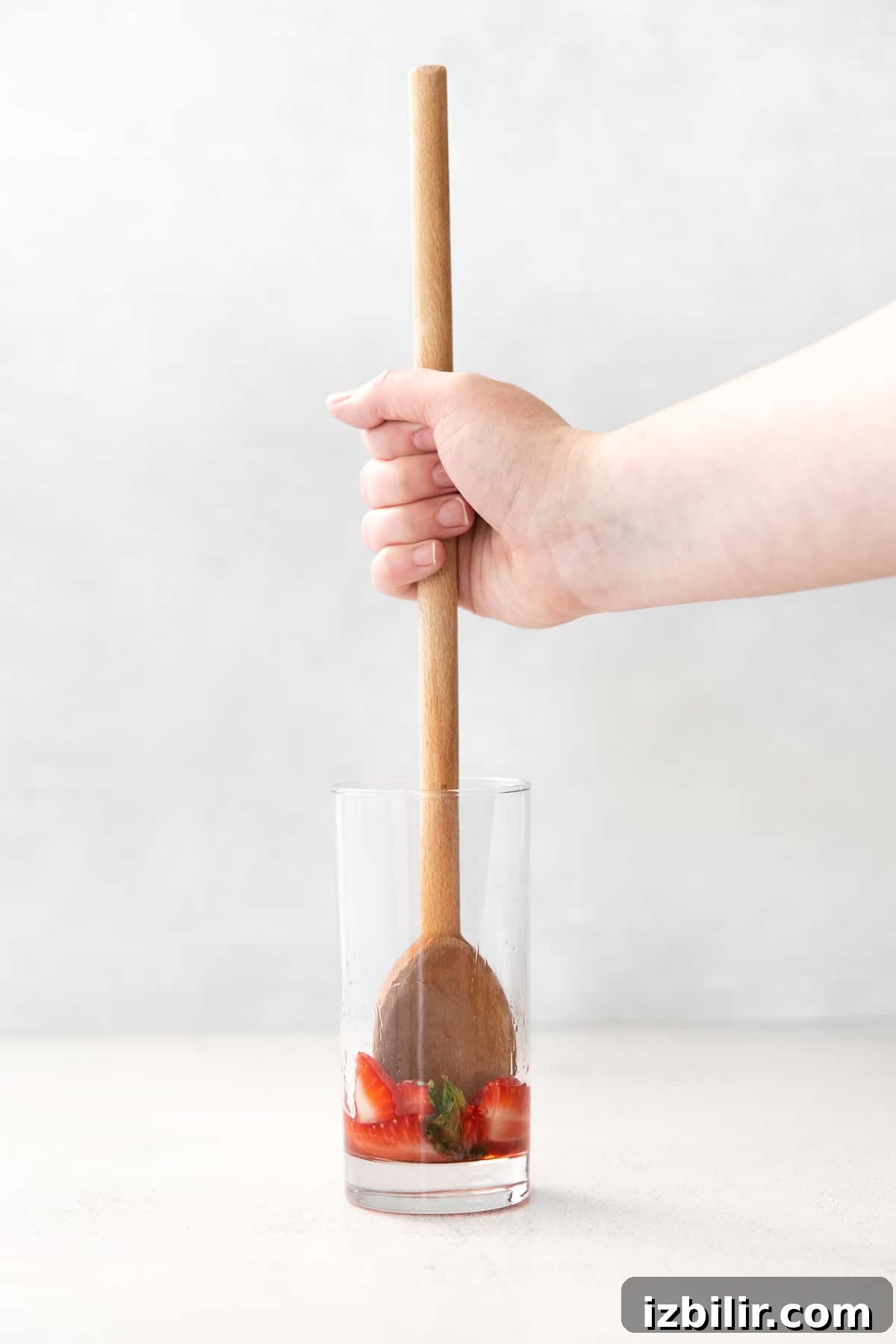 Muddling strawberries and mint in a glass