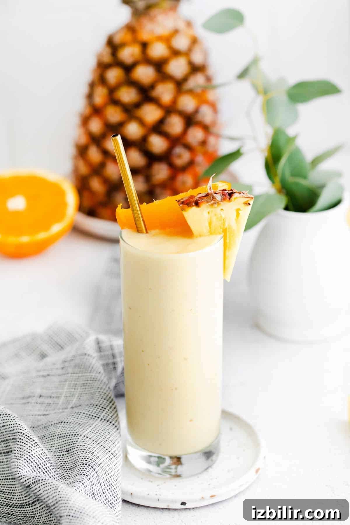 This pineapple smoothie recipe is so refreshing it tastes like vacation. It's made with frozen pineapple, banana, Greek yogurt, and pineapple juice! pineapple smoothie with orange and pineapple chunks