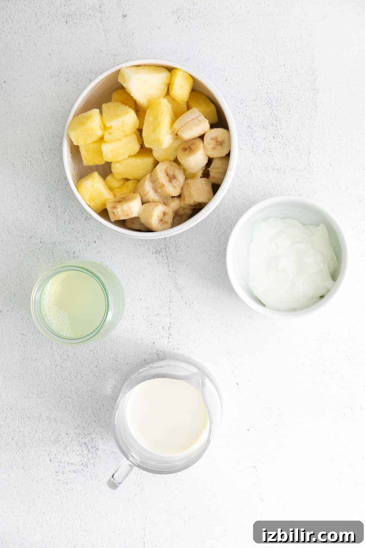 This pineapple smoothie recipe is so refreshing it tastes like vacation. It's made with frozen pineapple, banana, Greek yogurt, and pineapple juice! pineapple, banana, Greek yogurt, pineapple juice, and almond milk on countertop