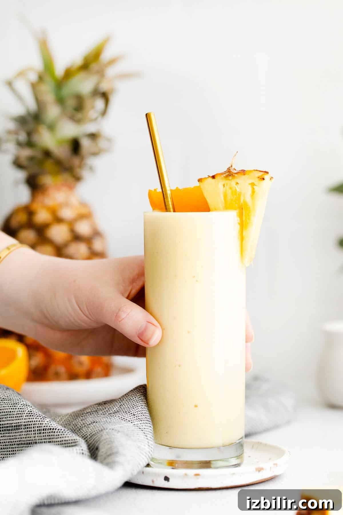 This easy pineapple smoothie recipe is made with frozen pineapple chunks, Greek yogurt, pineapple juice, and a banana. It tastes like tropical paradise! hand holding pineapple smoothie