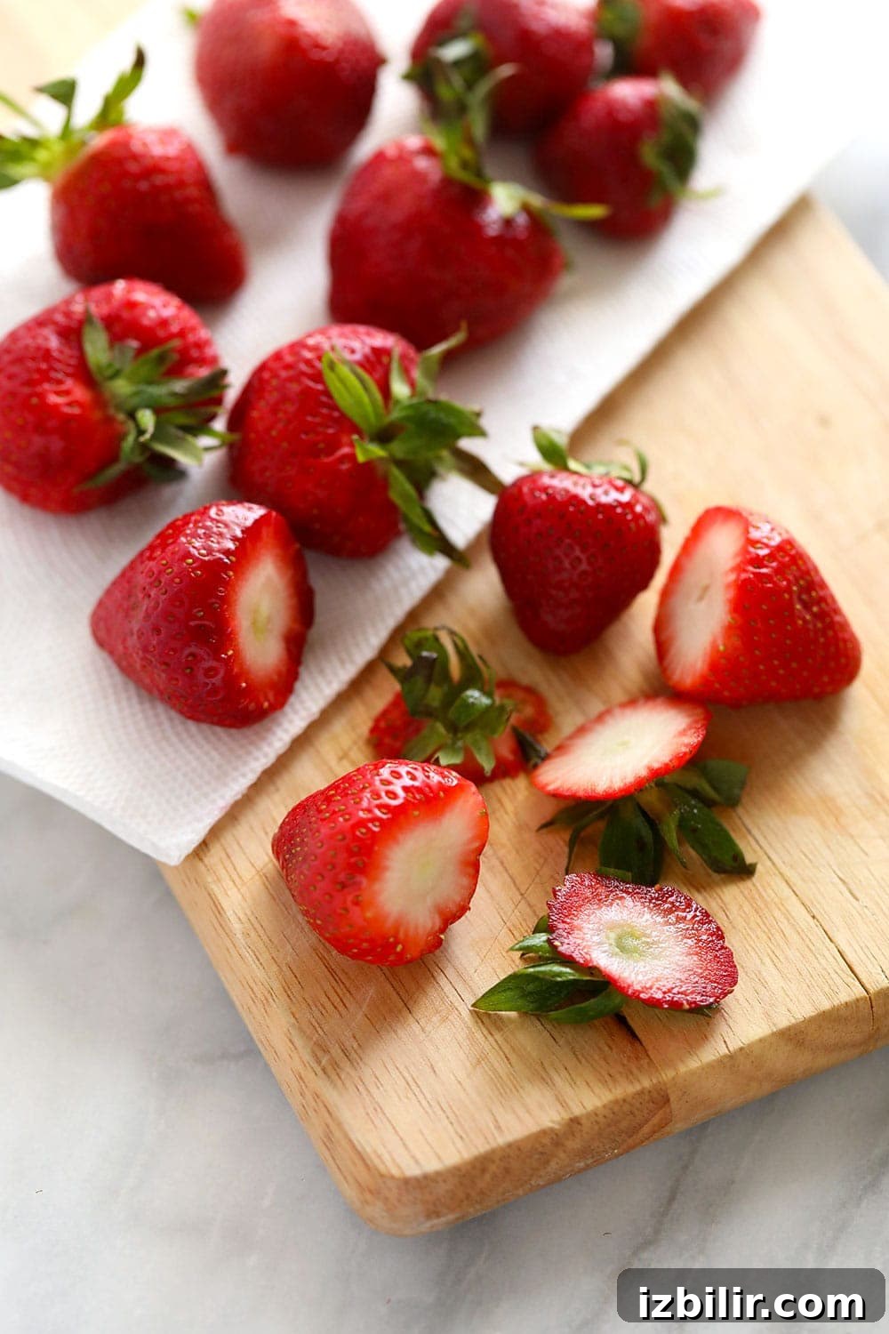 How to Freeze Strawberries Without Freezer Burn 3 Cutting the tops off fresh strawberries before freezing them.