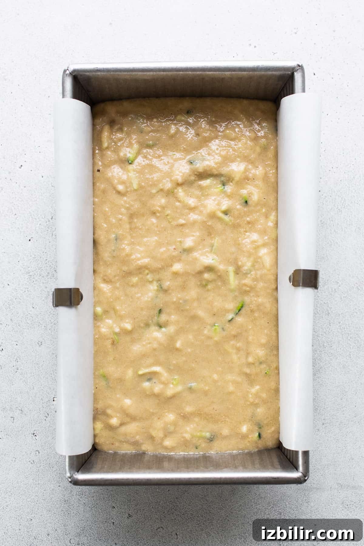 Moist Zucchini Bread with Cinnamon and Walnuts 5 A metal pan filled with food on top of a table.